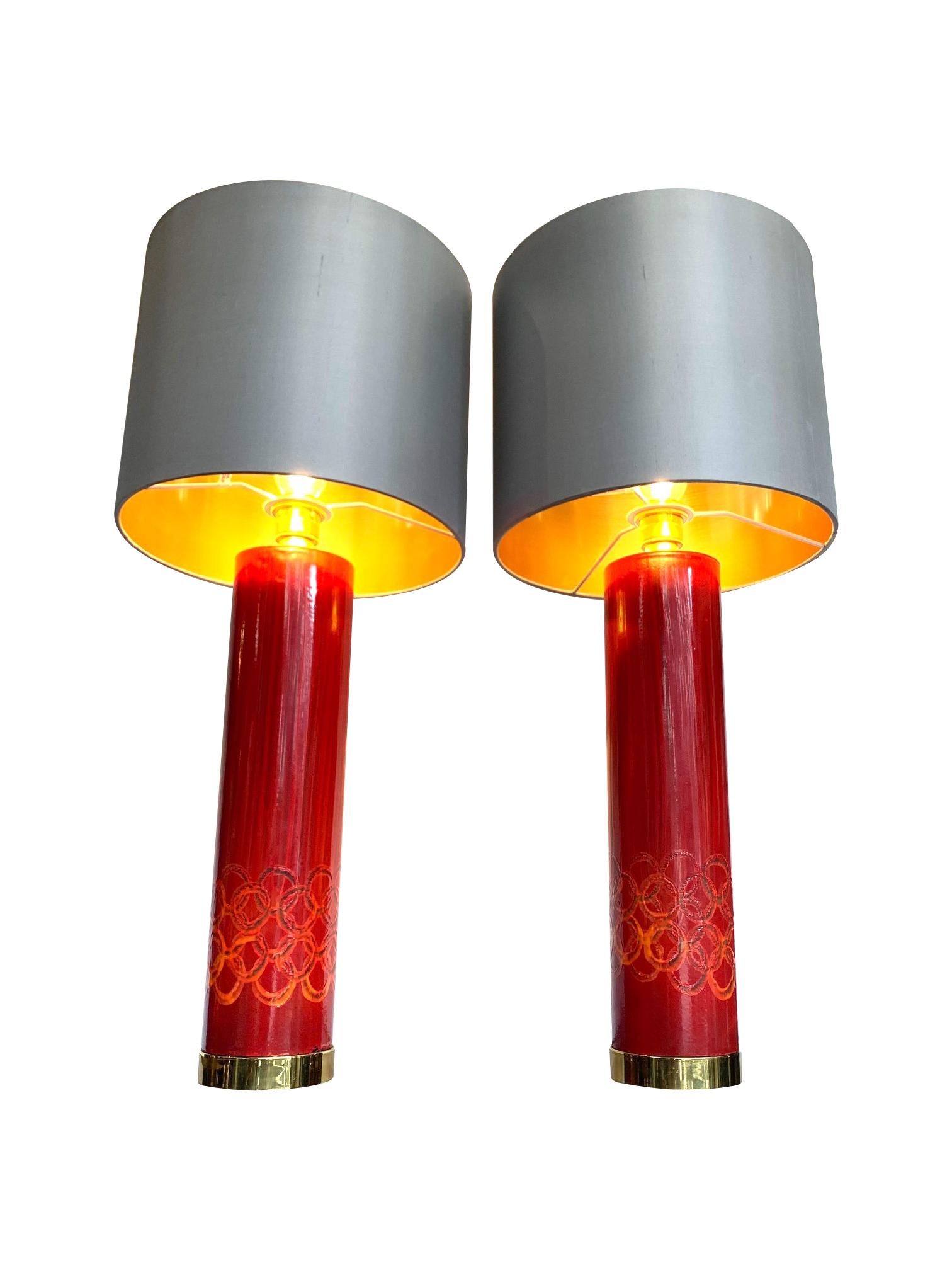 A lovely pair of Swedish red ceramic lamps each with circular orange ceramic detail on the bottom of the base. With brass fittings and top plates, mounted on brass bases. Re wired with new fittings, antique gold cord flex and PAT tested. Both with