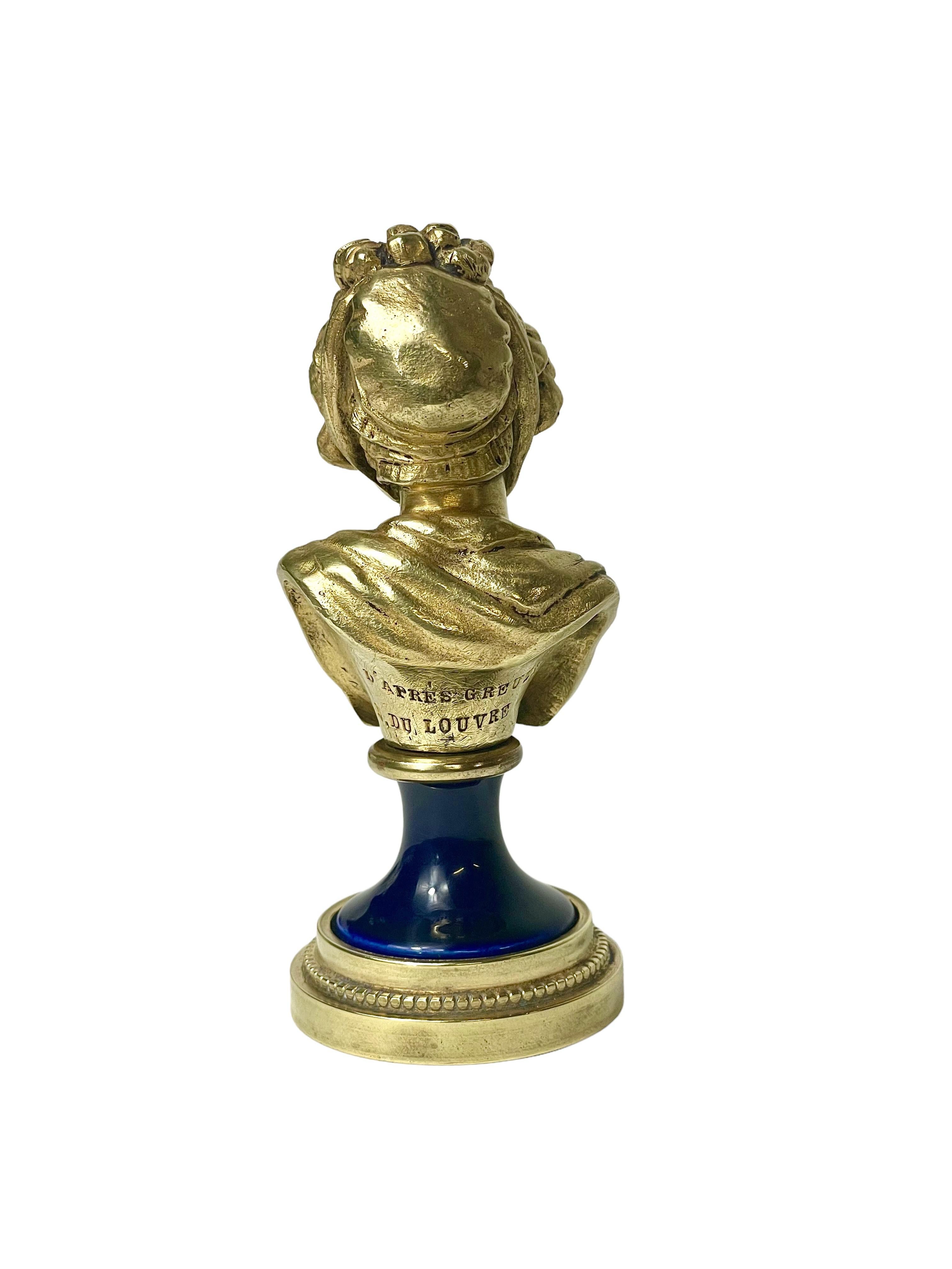A lovely gilt bronze bust depicting an elegant young lady, with fashionable frilled bonnet, finely draped clothing and a serene expression. Mounted on a deep blue porcelain and bronze base, the Louis XVI style statuette (circa 1900) is inscribed on