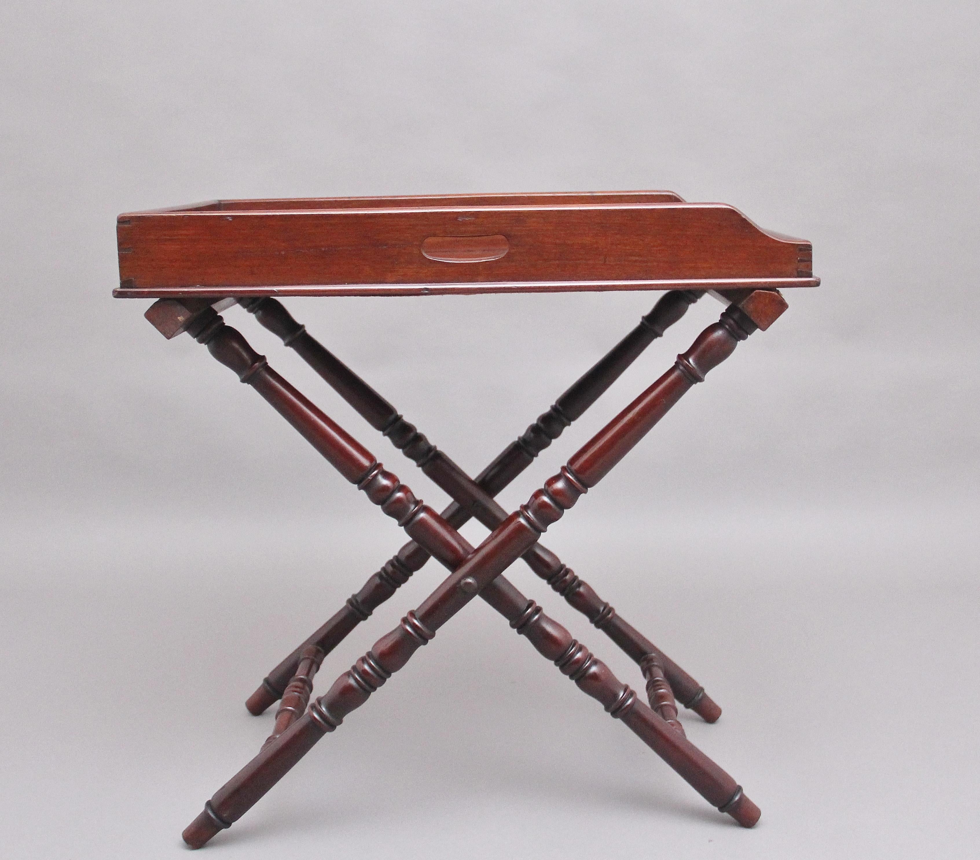 A lovely quality early 19th century mahogany butlers tray on stand, the rectangular shaped tray with a surround gallery three quarters raised and with two fret cut carrying handles above a folding stand. Circa 1830.