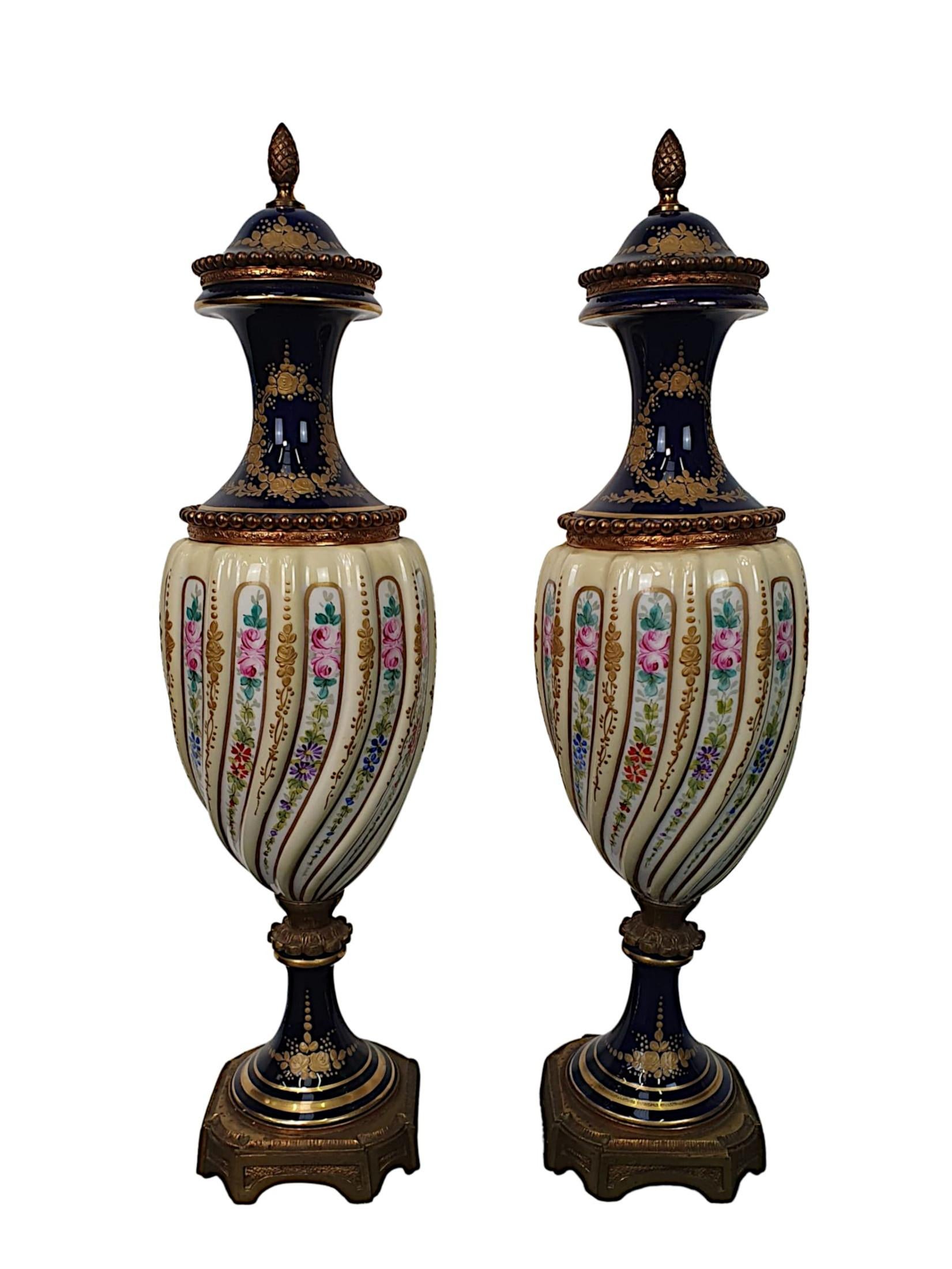 A lovely quality pair of 19th century porcelain and ormolu mounted lidded urns in the manner of Sèvres. The lids with acorn finial raised over a classic baluster vase body with beaded motif detail. Intricately hand painted throughout with decorate