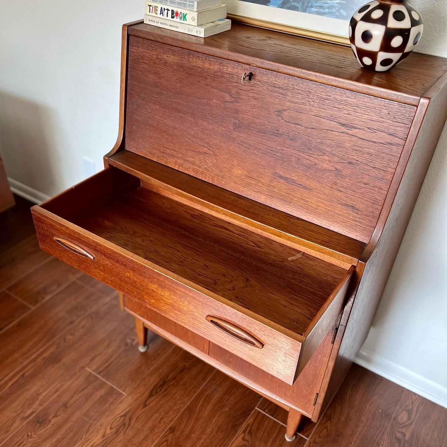 A lovely teak veneered sewing box from the 1960s, unmarked. The top extends with a fold out flap & there’s a pull out wicker basket underneath with a partitioned drawer above. In great original condition.

Dimensions:
25