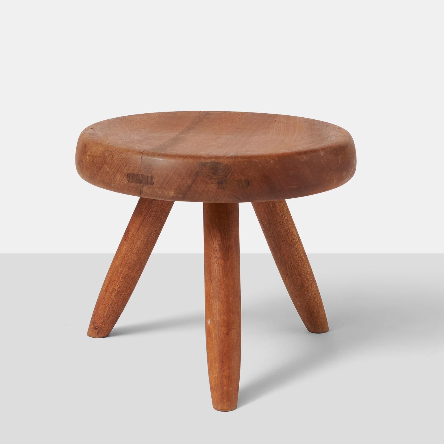 A rare low stool in mahogany with three tapered legs by Charlotte Perriand. 
France, circa 1950s.  One stool remains available.