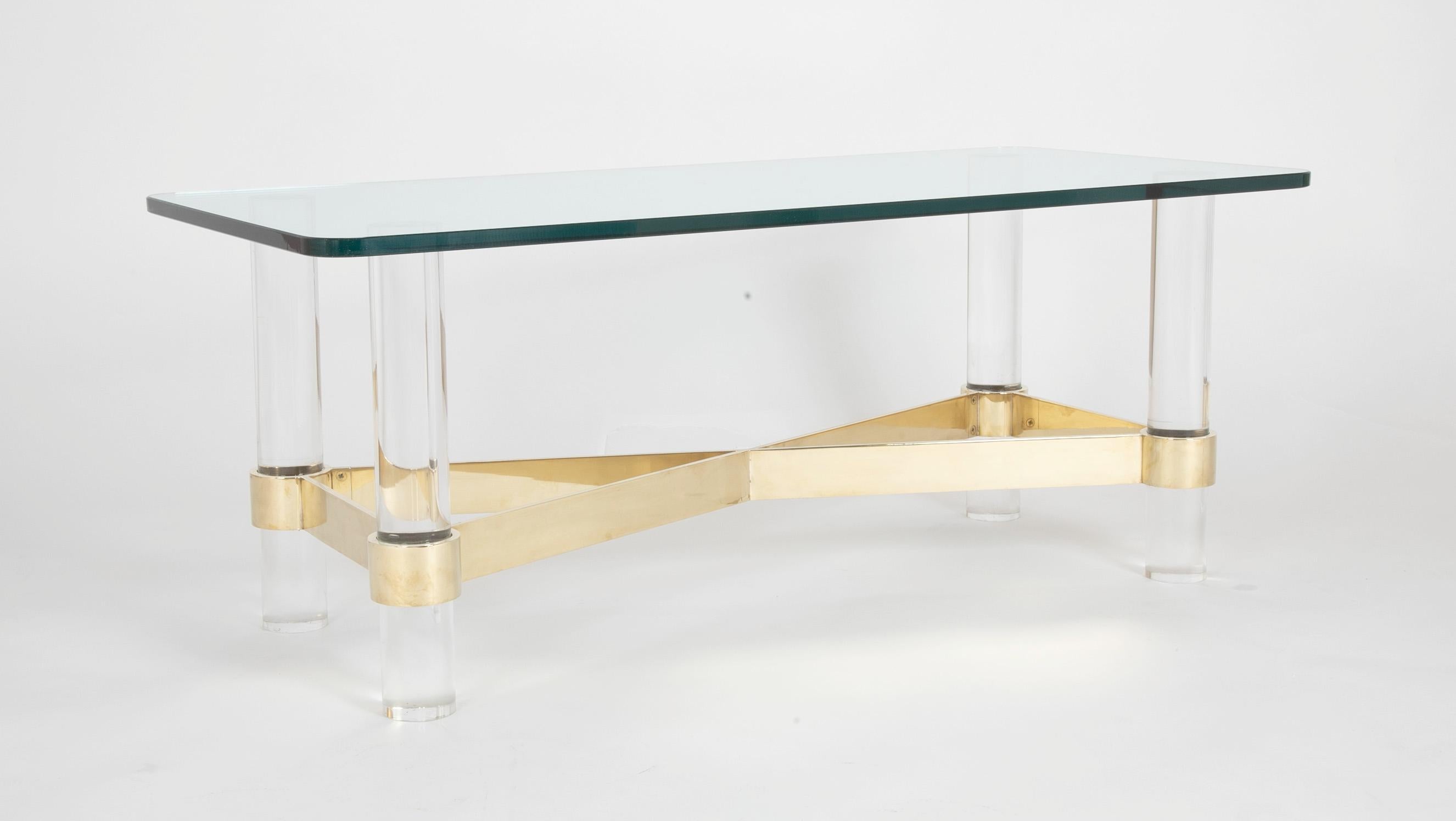 A Karl Springer style glass top coffee table with Lucite legs and heavy brass stretcher.
