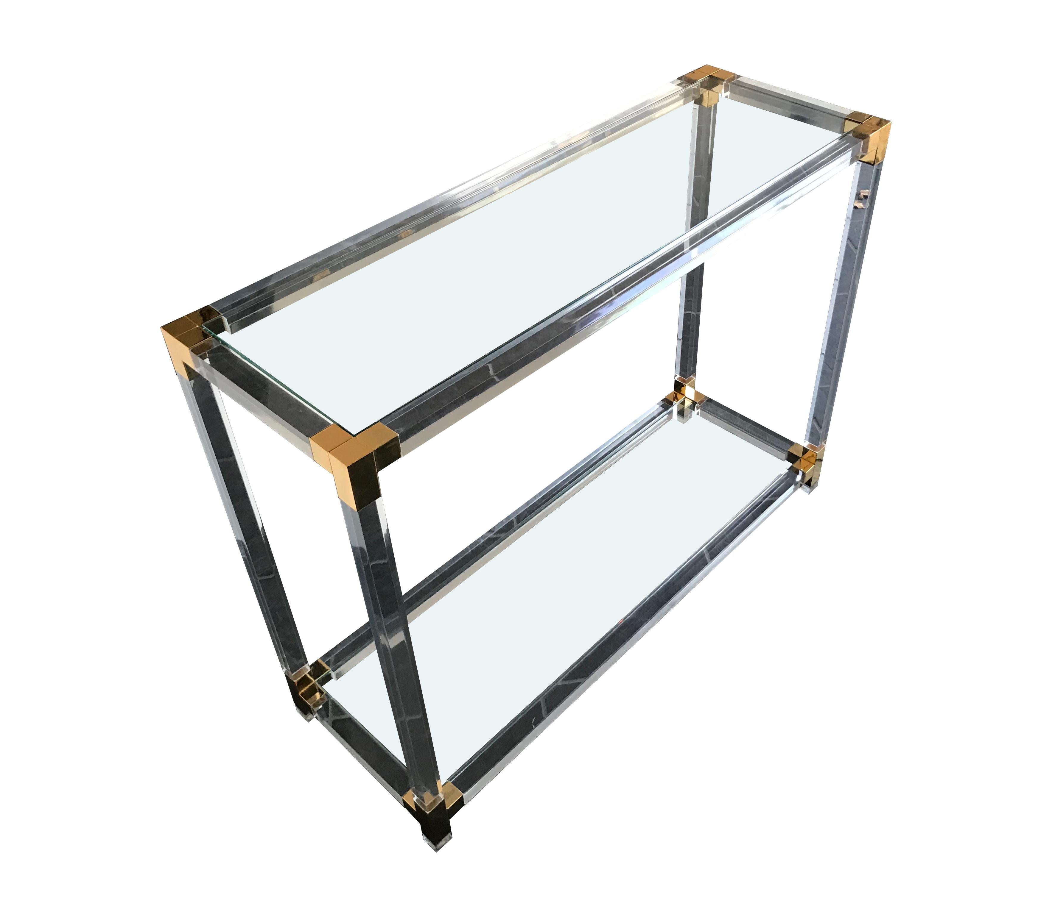 A Lucite console table with gilt metal corner joints and 2 clear glass shelves.