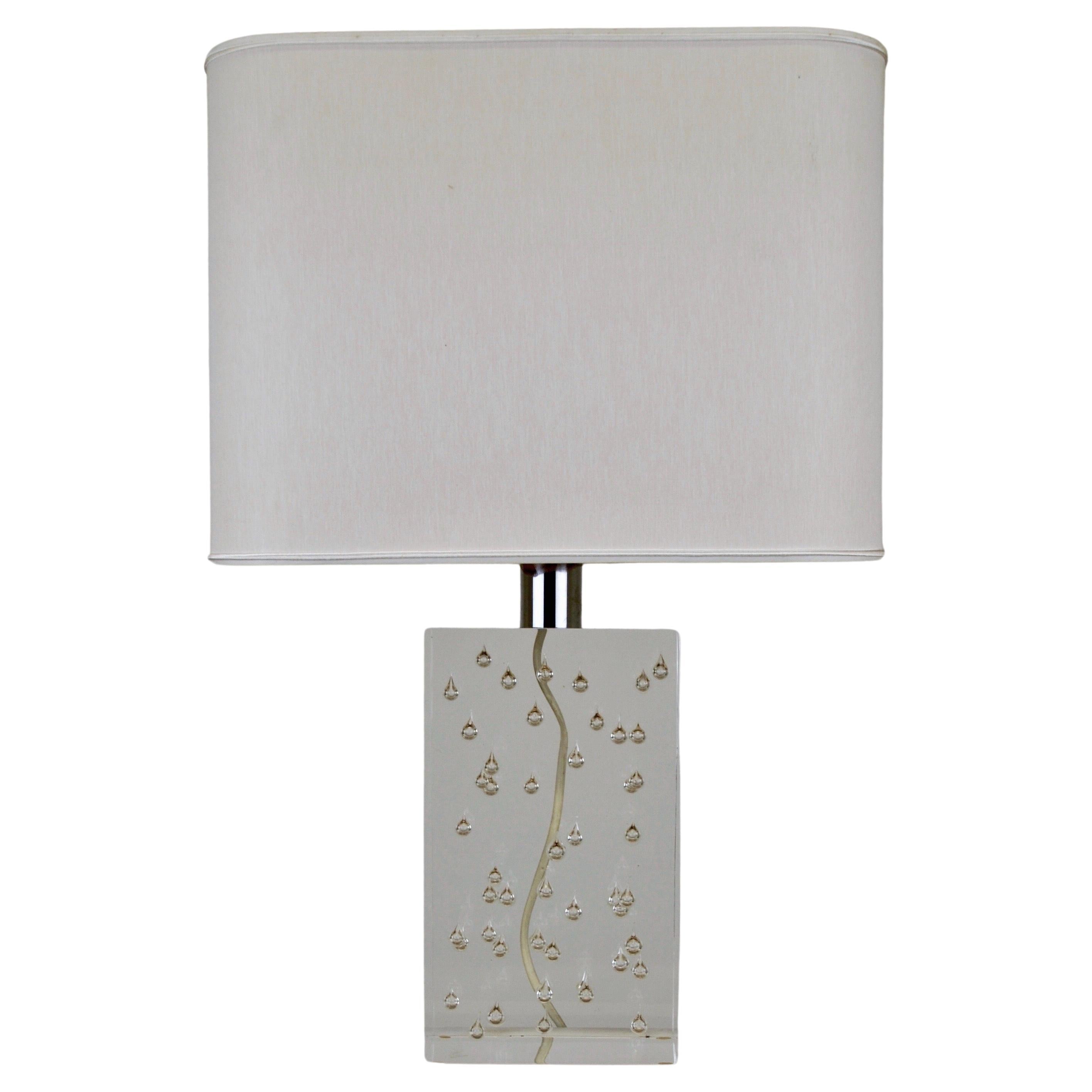 A rare and exceptional lamp by Pierre Giraudon, crafted from transparent lucite, distinguished by its unique design. Inside the lucite, droplets resembling tears are encapsulated, creating a mesmerizing play of light when the lamp is illuminated.