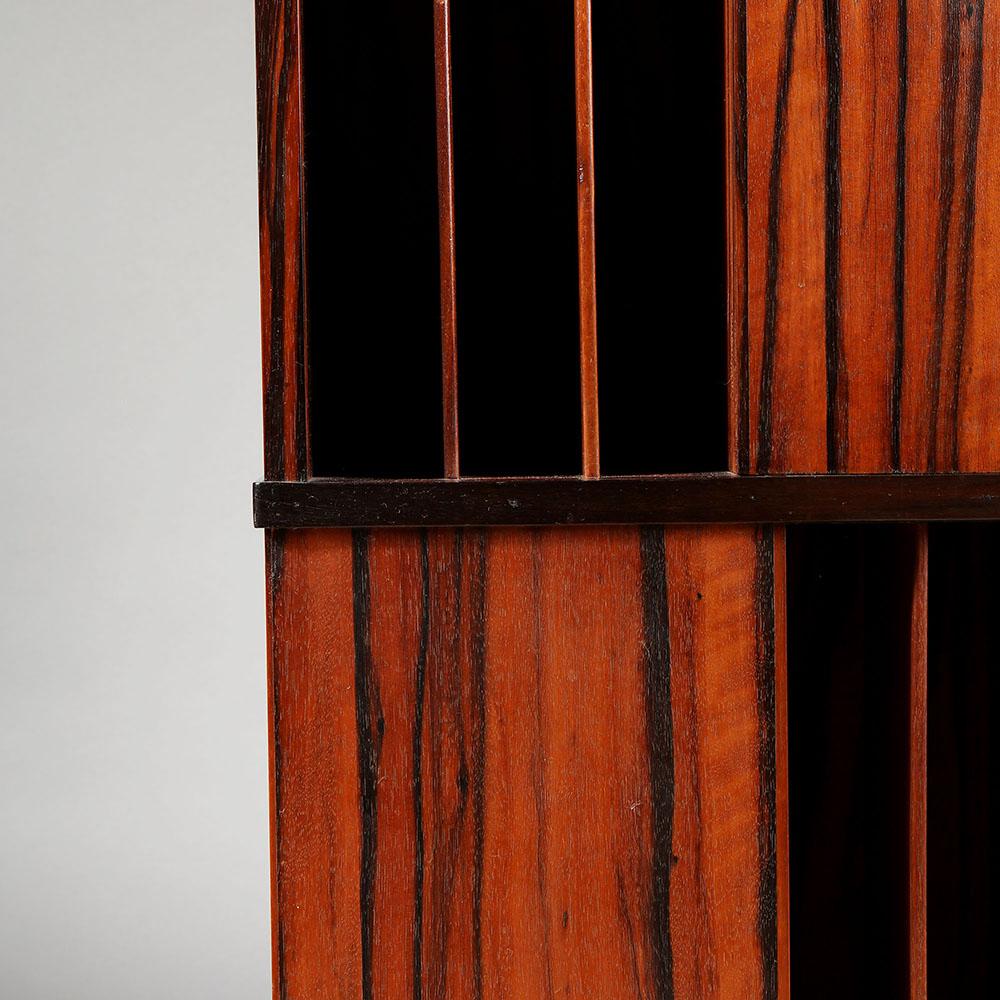 A Macassar ebony revolving bookcase, six thin shelves to each face, bun feet to the base.