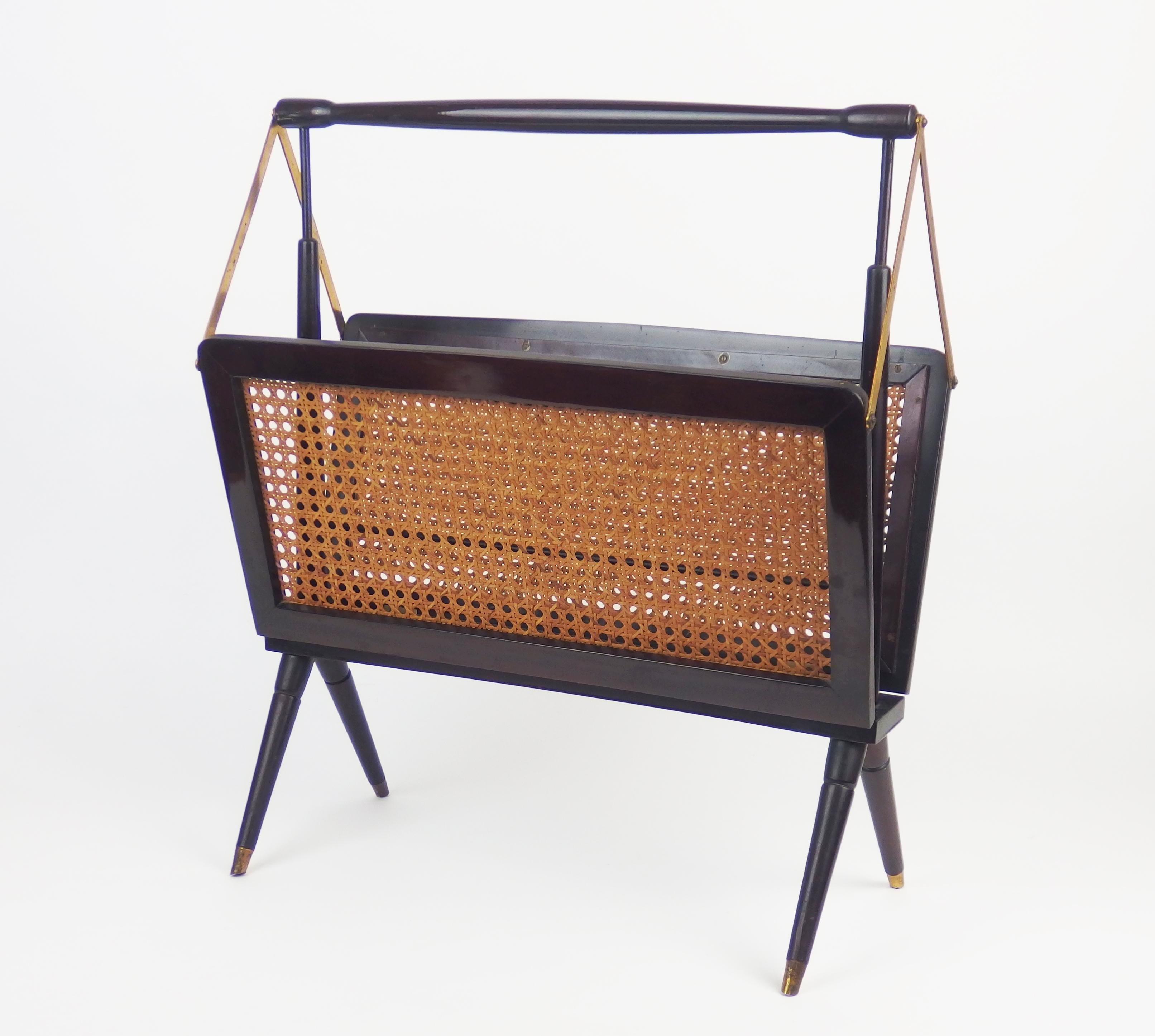 A folding magazine rack in mahogany and brass with cane on both sides.