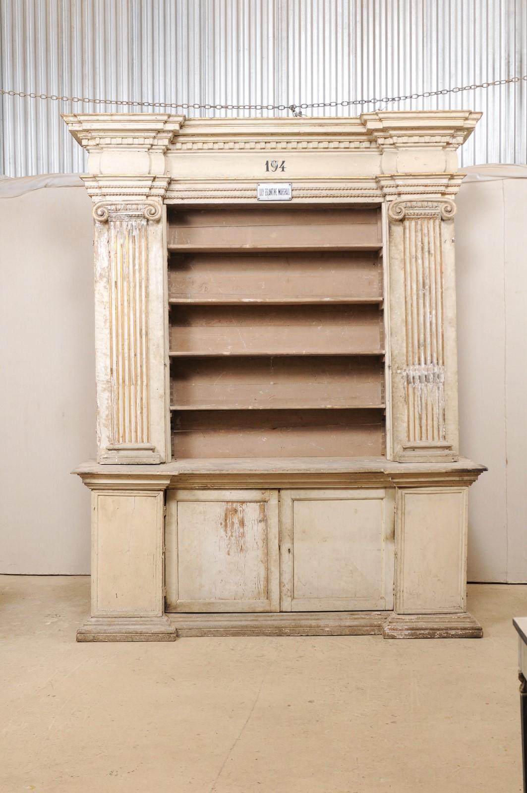 An 18th century open shelving display and closed storage cabinet from Italy, with fabulous Roman Ionic column details and retains it's original paint and gilt accents. This antique cabinet, which originally resided in an old church in Italy, is very