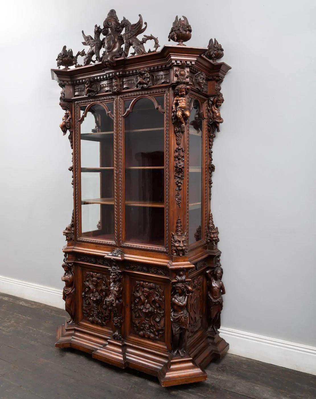 Magnifique bibliothèque ancienne en noyer fabuleusement sculptée dans le style renaissance. 
Profondément sculpté de figures masculines, de putti, de griffons, de masques, de feuillages et de moulures profondes.

La base comporte deux portes de