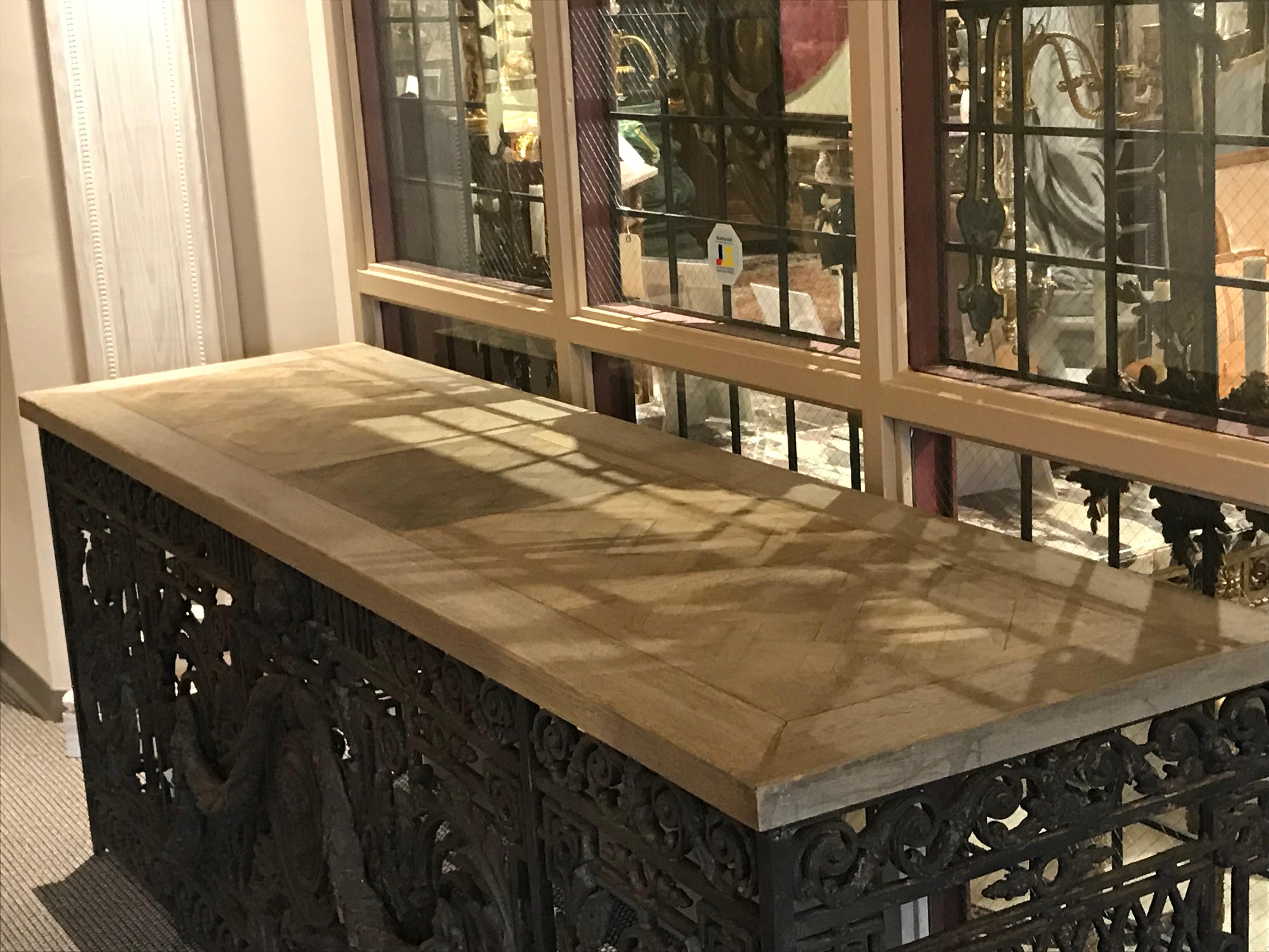 A Superb French Cast iron balcony, Renaissance style, attributed to Val D'Osné foundry cooperative in Paris, with trilage sides, female images, lions and laurel guards, now turned into console. The wooden top featuring Antique Oak Versailles Parquet