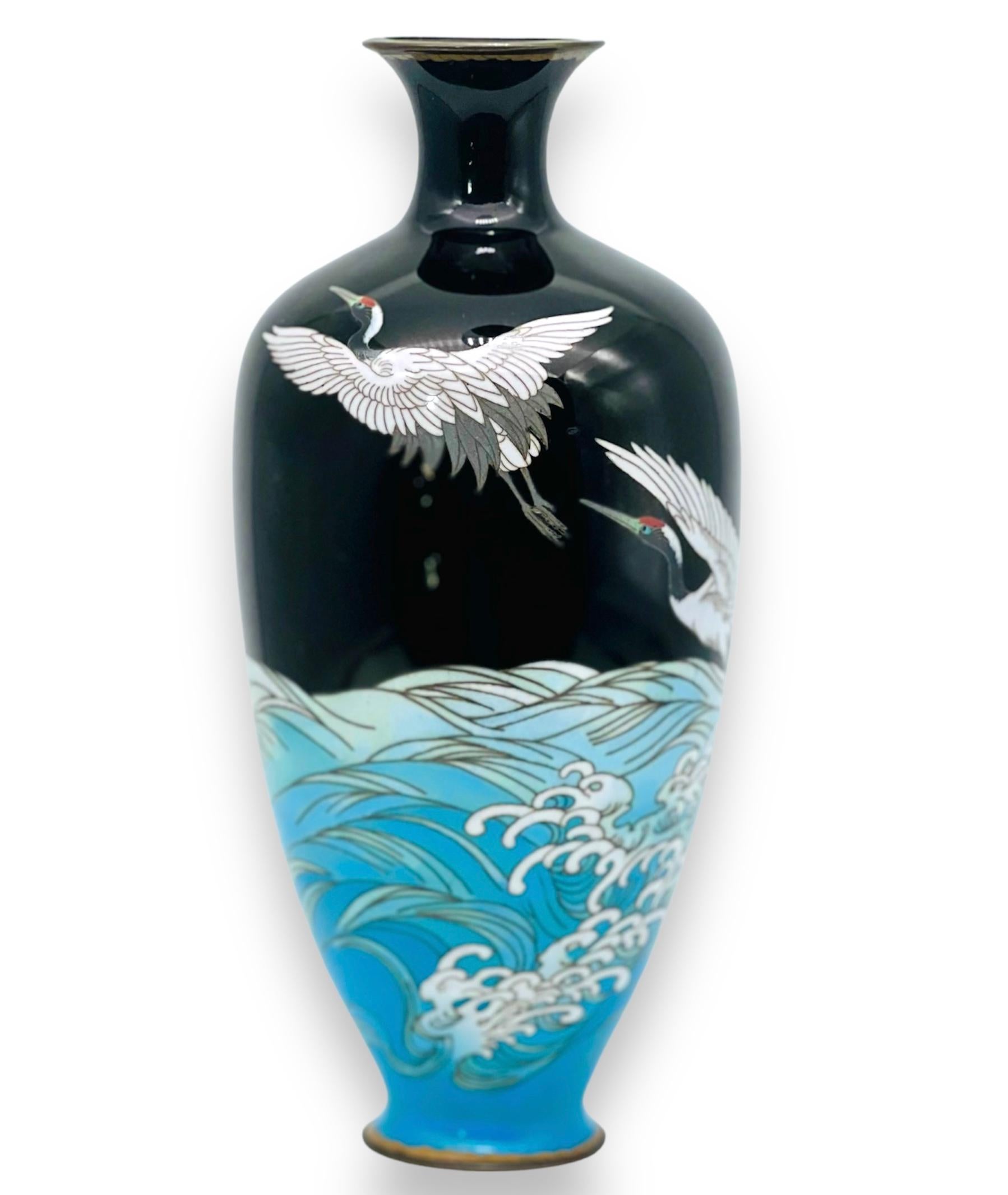 A magnificent Japanese cloisonne enamel Vase. Signed. Meiji period 

of tapering form with everted neck, decorated in various coloured enamels with two cranes in flight above the crashing waves on a mirror black background, the rims mounted with