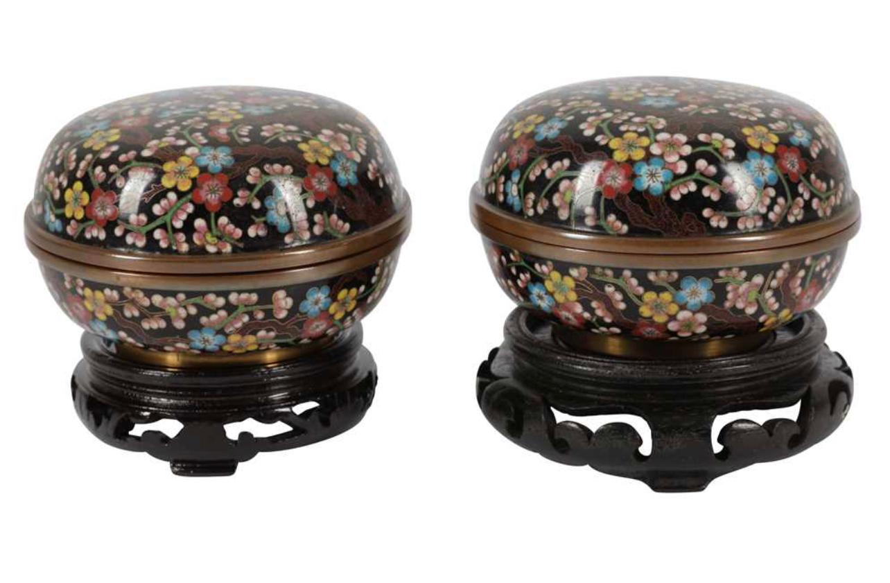 
A PAIR OF JAPANESE CLOISONNE ENAMEL BOXES AND COVERS, 19TH CENTURY, each decorated with polychrome tree blossom on black ground, the insides enamelled with blue, each resting on pierced wooden stands, the boxes 10cm diameter .

In good condition.