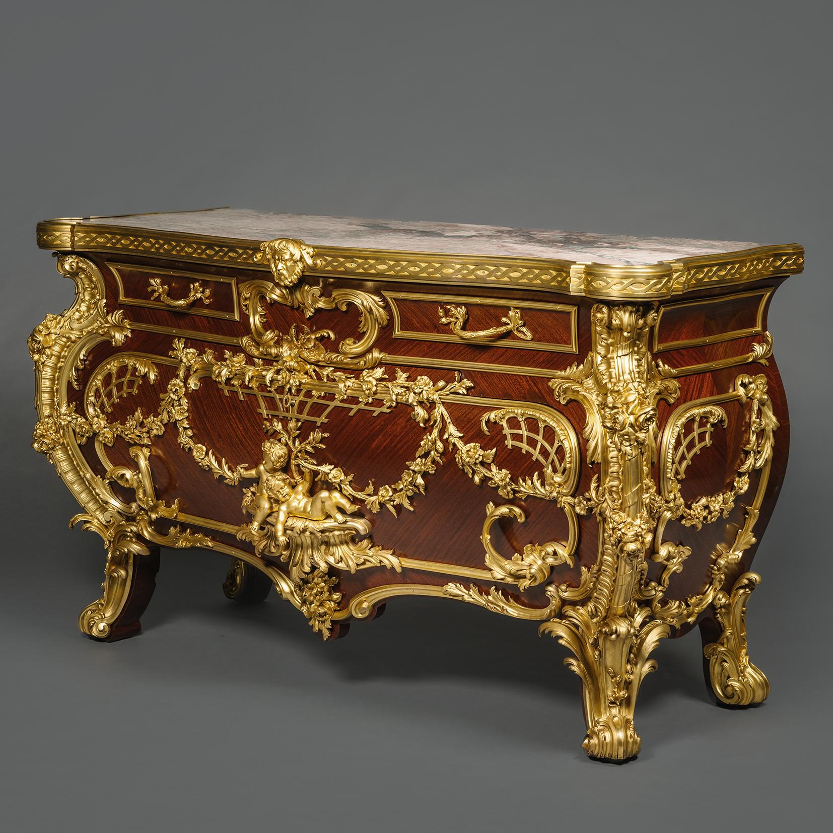 Magnifique commode de style rococo en bronze doré, bois satiné et acajou.
Par Rosel, Bruxelles, d'après le célèbre modèle de Johann Melchoir Kambli. 

De forme bombée, elle est surmontée d'un marbre des Pyrénées de Campan, veiné de vert et de rose,