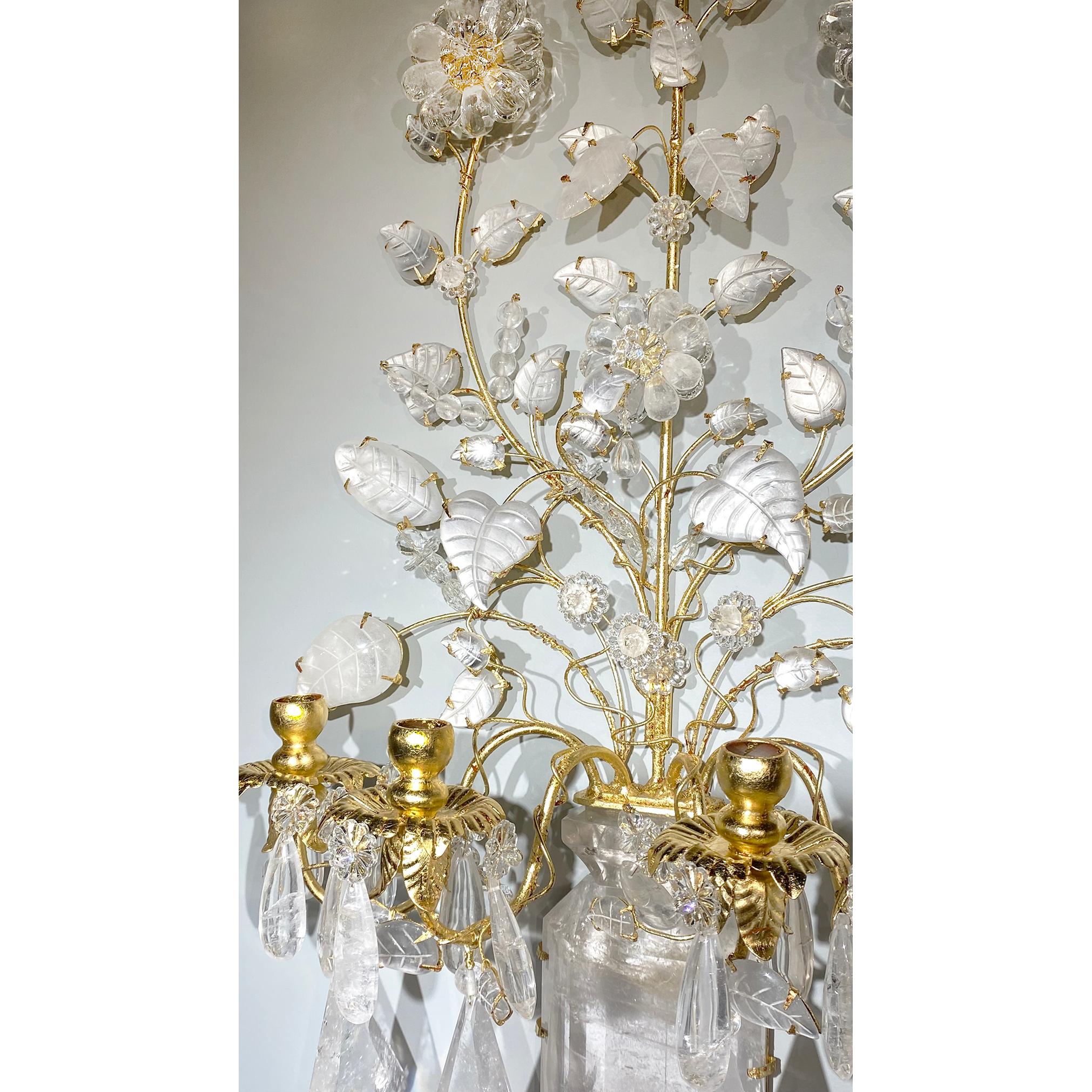 A great pair of rock crystal sconces in Bagues style. An angular vase shaped base made of rock crystal anchors the four gilt bronze lights of the sconce. Decorative floral and leaf accents carved in rock crystal bloom out of the base, creating a