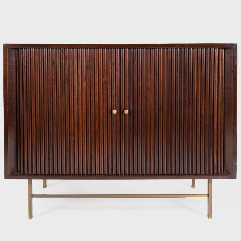 A tambour door mahogany cabinet rising on brass armature legs. In the manner of Harvey Probber, circa 1950s.
