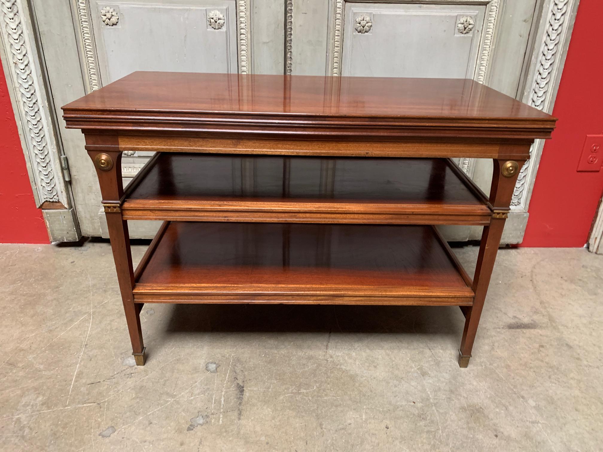 A neoclassical style flip top metamorphic tea table with a pullout tray attributed to Maison Jansen in mahogany with brass fittings.