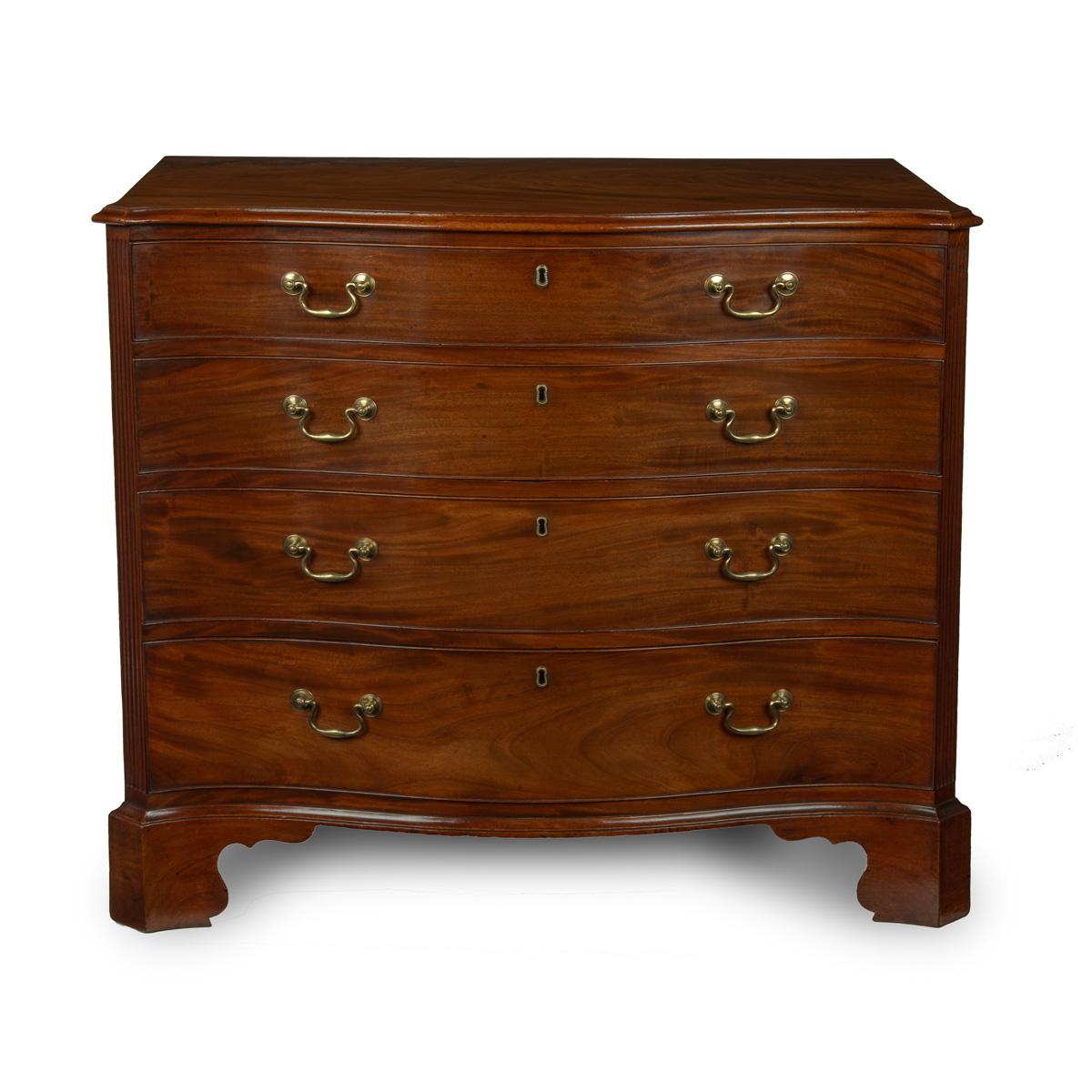 A George III mahogany four-drawer serpentine chest of drawers, the shaped top with fluted cut corners, with four graduated drawers, orginal  brass handels and bracket feet. English, circa 1790.

