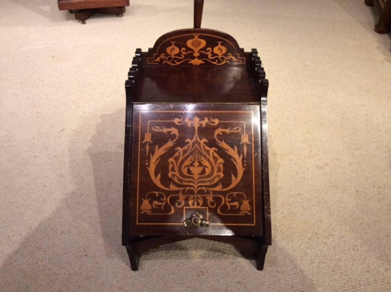 A mahogany inlaid Arts & Crafts Period coal perdonium. The raised back with stylized art nouveau marquetry inlaid detail and castellated sides. With a sloping front also with fine quality stylized marquetry detail and a copper handle, opening to