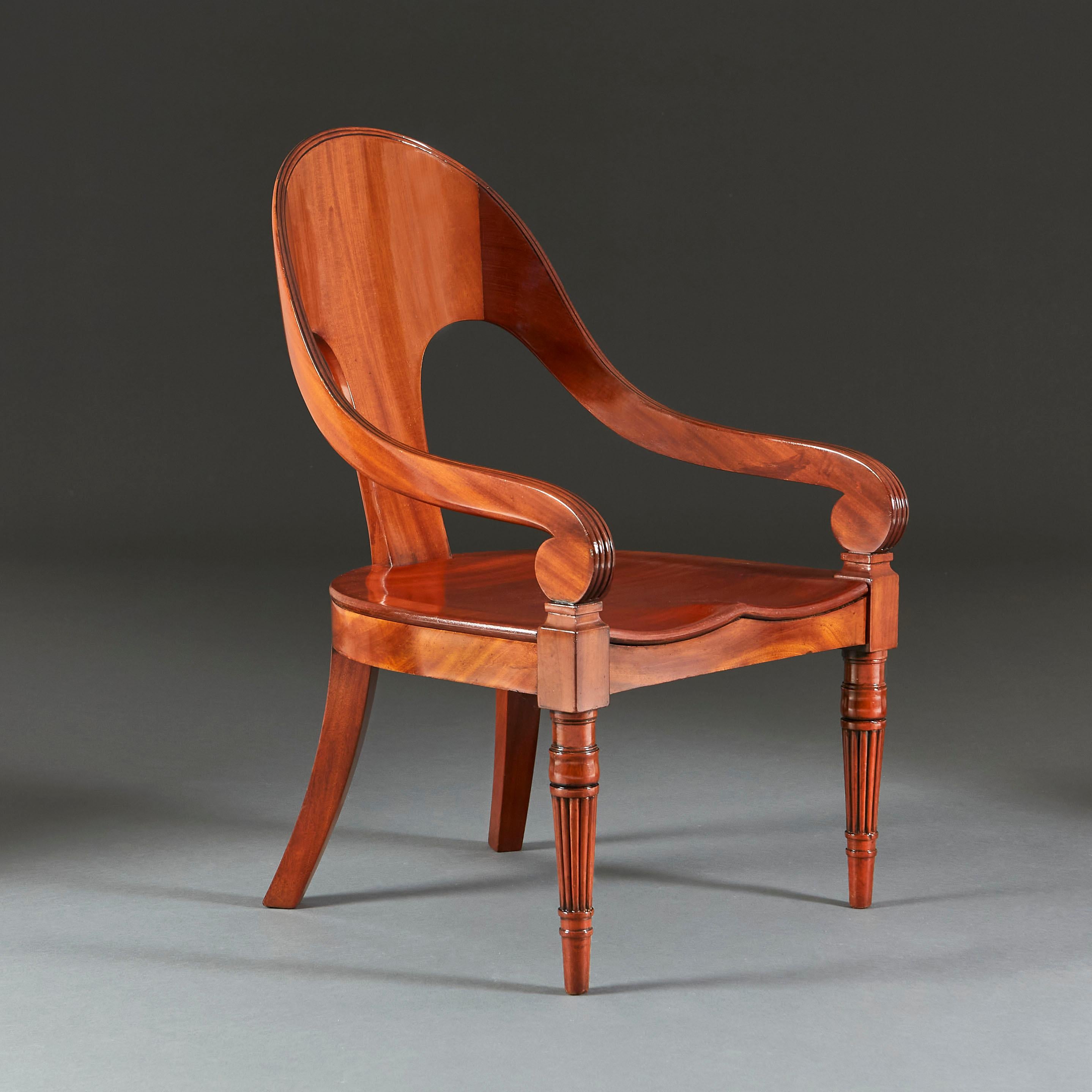 An early nineteenth century mahogany klismos chair with curved back, saddle seat, supported on fluted feet.