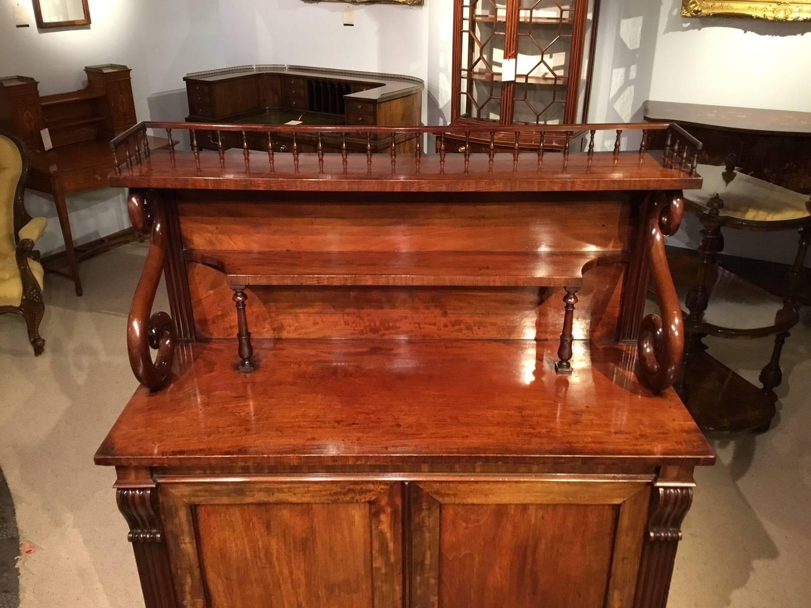 A mahogany Regency period antique chiffonier possibly by Gillows of Lancaster. The upper section with a turned spindle balustrade gallery above a shelf supported by S shaped scrolls, with a further shaped shelf and reeded pilasters. The lower