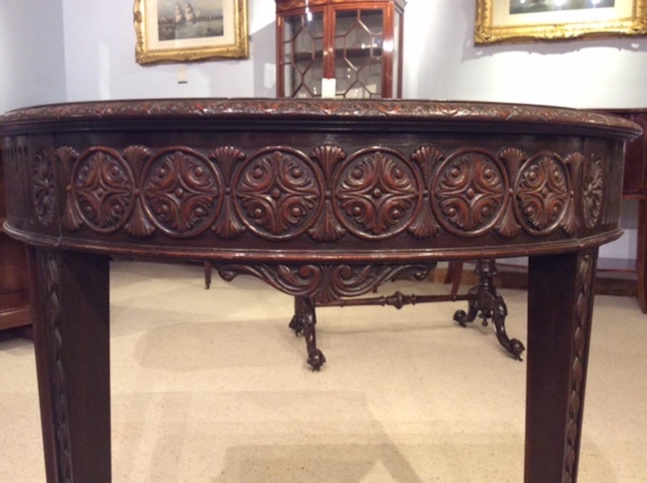 A mahogany Robert Adam Design demilune side/console table. Having a solid mahogany top with a carved moulded edge, above a finely carved frieze with oval carved paterae. Supported on elegant square tapering supports with carved trailing harebells