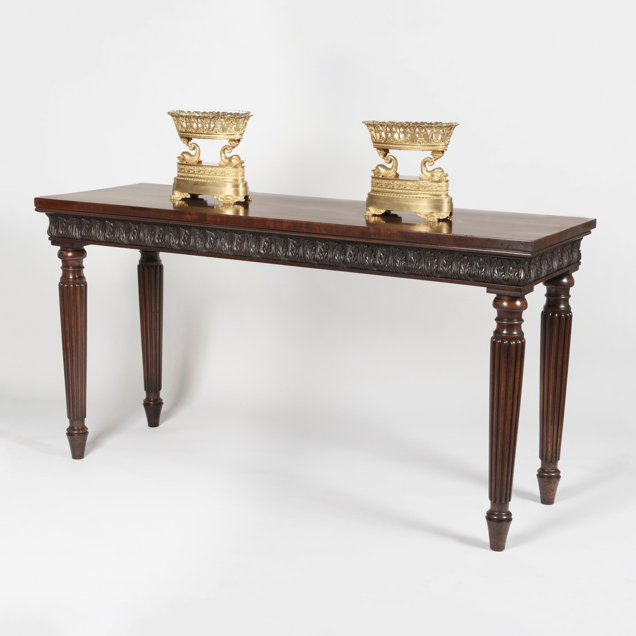 A fine George IV serving table

Constructed from richly patinated mahogany, the rectangular serving table rising from turned and tapering reeded legs; the top supported by a carved acanthus & lotus running frieze.
Circa 1825.
 