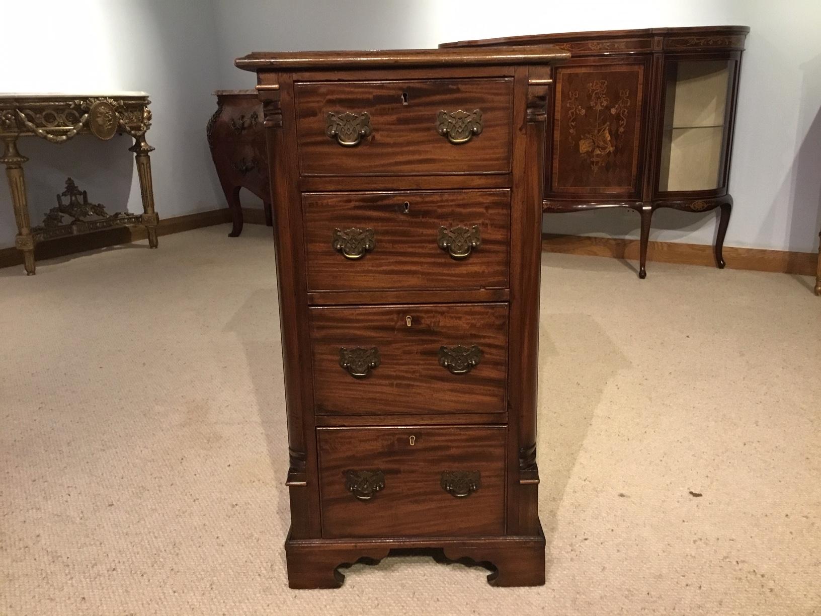 A mahogany Victorian Period antique pedestal chest. The rectangular solid mahogany top above an arrangement of four mahogany lined drawers with period style brass swan neck handles, quarter rounded columns, solid mahogany sides and supported on