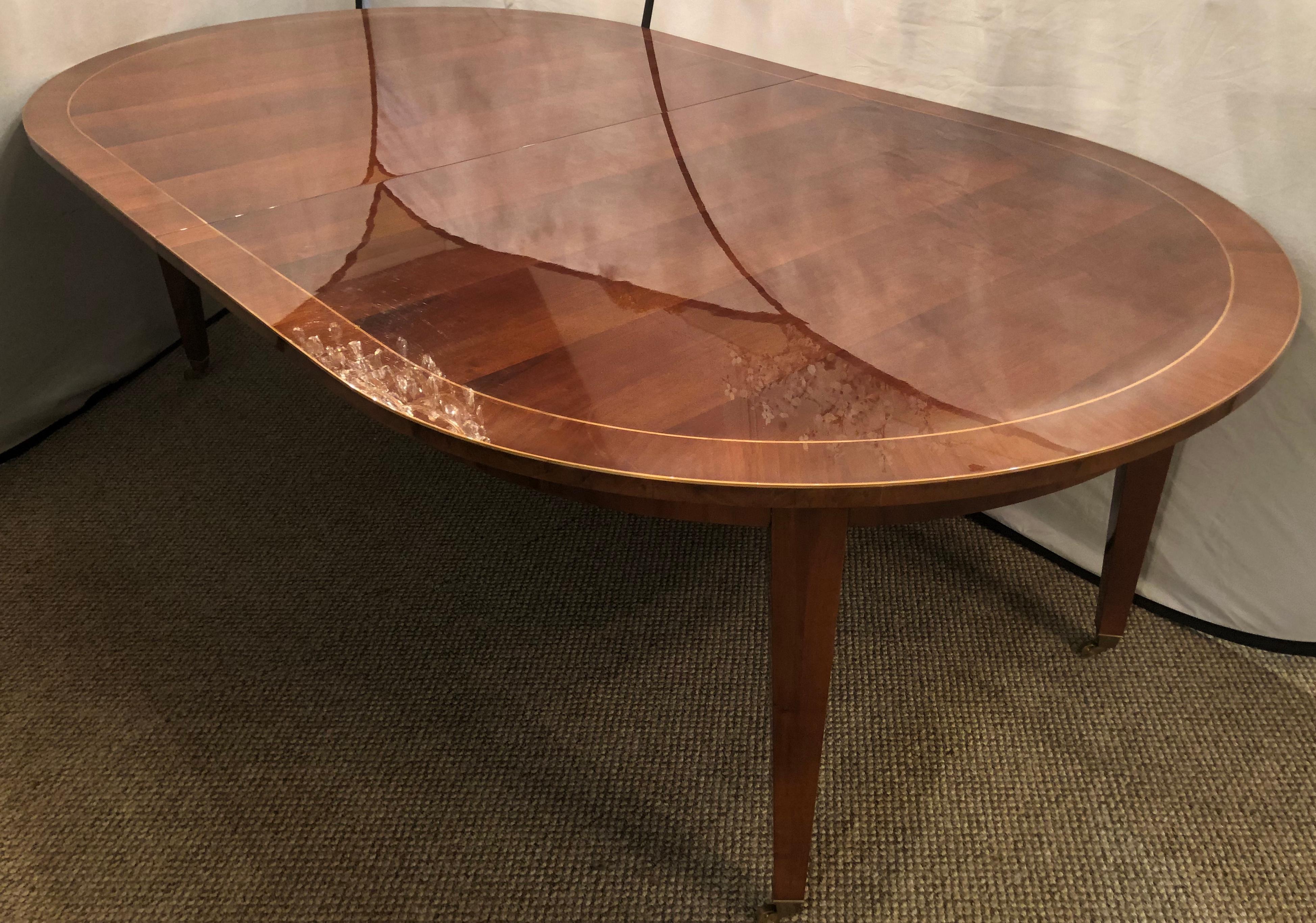 A Maison Jansen inspired dining table by Iliad Design. This Fine 54 inch wide custom made flame mahogany neoclassical dining table having one 24 inch leaf was purchased directly from Iliad Design for over thirty thousand dollars by the current