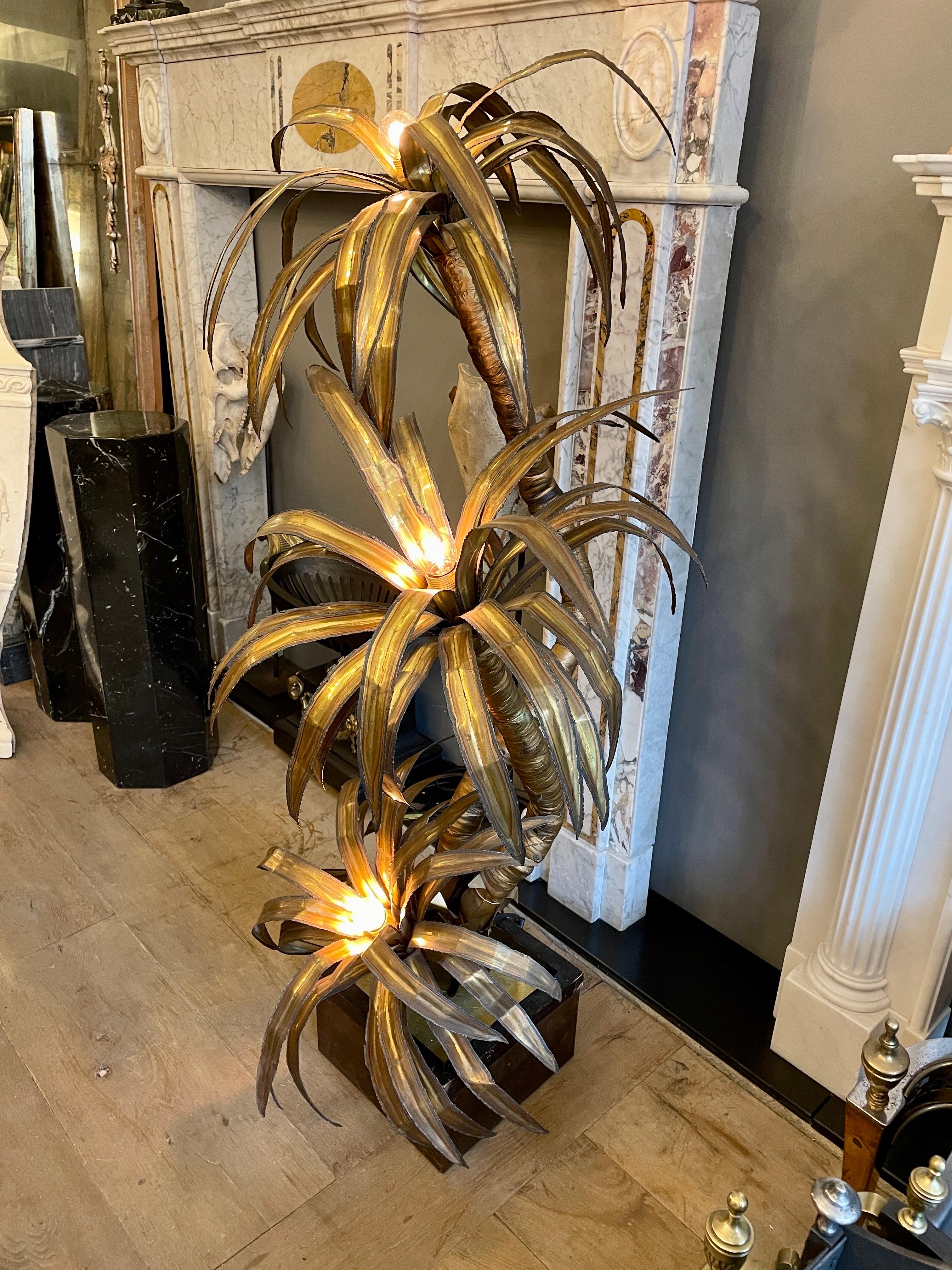 A large 3 headed palm tree floor lamp by Maison Jansen Paris.
The burnished and patinated leaves of the three heads with bulbs to centre. The stem wrapped in fabric and distressed gold finished. The burnished base with timber framed edge. An