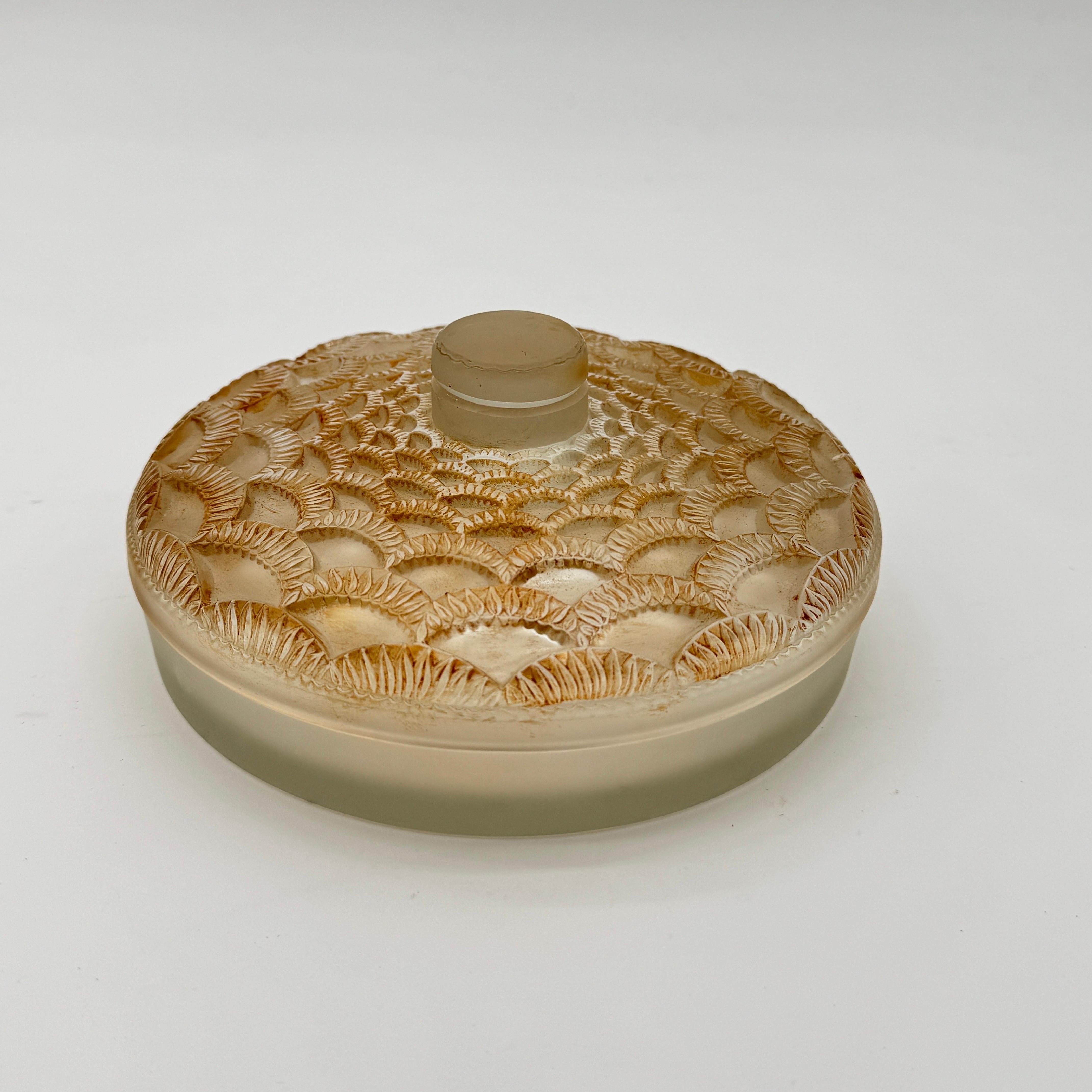 Die Festons Boxe wurde in den 1940er Jahren von Marc Lalique für Maison Lalique entworfen.

Die Boxen  ist in ausgezeichnetem Zustand mit brauner Patina und einer handschriftlichen Unterschrift in Schreibschrift.

