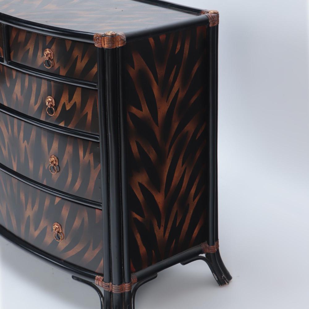 A single Maitland Smith ebonized five drawer bow front commode having flame decoration and leather wrapped trim. Each drawer is adorned with lion face drawer pulls.