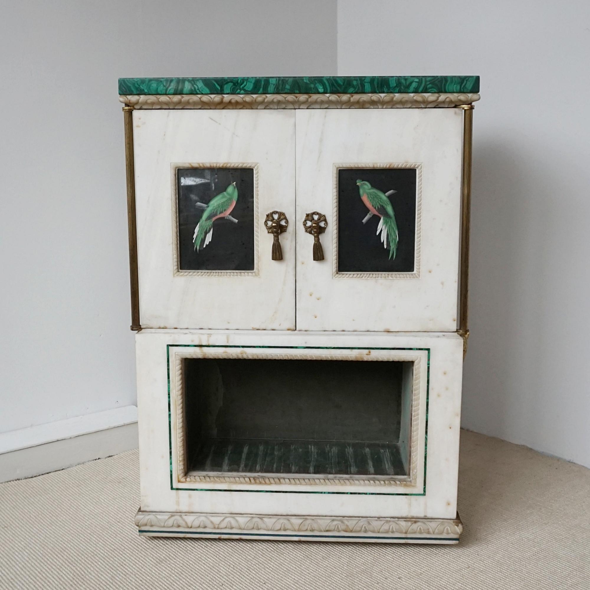Armadio a due ante in marmo e malachite con inserto aperto foderato in velluto verde alla base. Pannelli dipinti a mano con uccelli tropicali e maniglie originali in ottone dorato.

Dimensioni: H. 92 cm. L. 66 cm. P. 48 cm.

Origine: italiana

Data:
