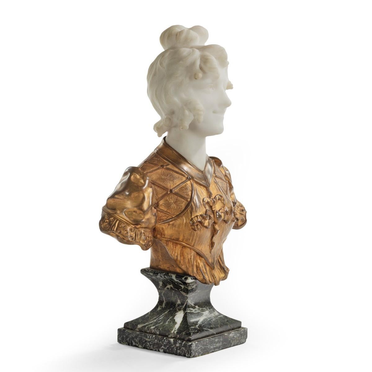 A marble and Ormolu bust by Marionnet, showing the white marble head and shoulders of a girl with her hair in a bun and ringlets framing her face, with a ruffled bodice with short sleeves and ribbons rendered in ormolu, all on a spinach marble