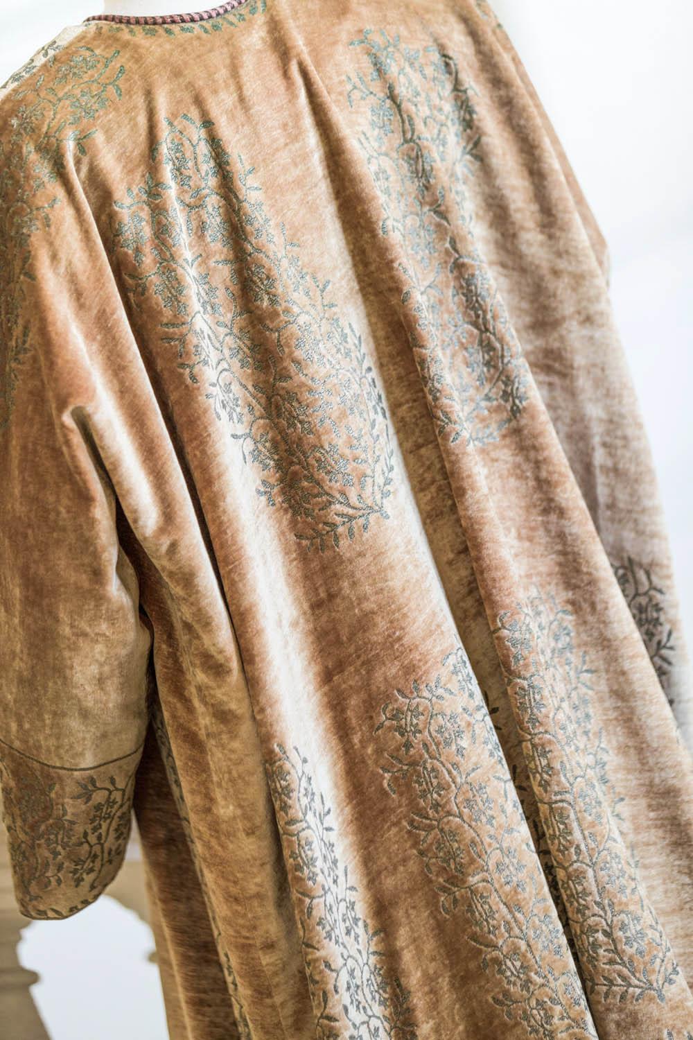 1915/1925
Venise Italy
A short kaftan coat with kimono sleeves in mandarin silk velvet. Gold printing of large cartridges with stylized floral decoration. Beige satin silk lining. Collar tied with a bicolor braid ended by two white Murano glass