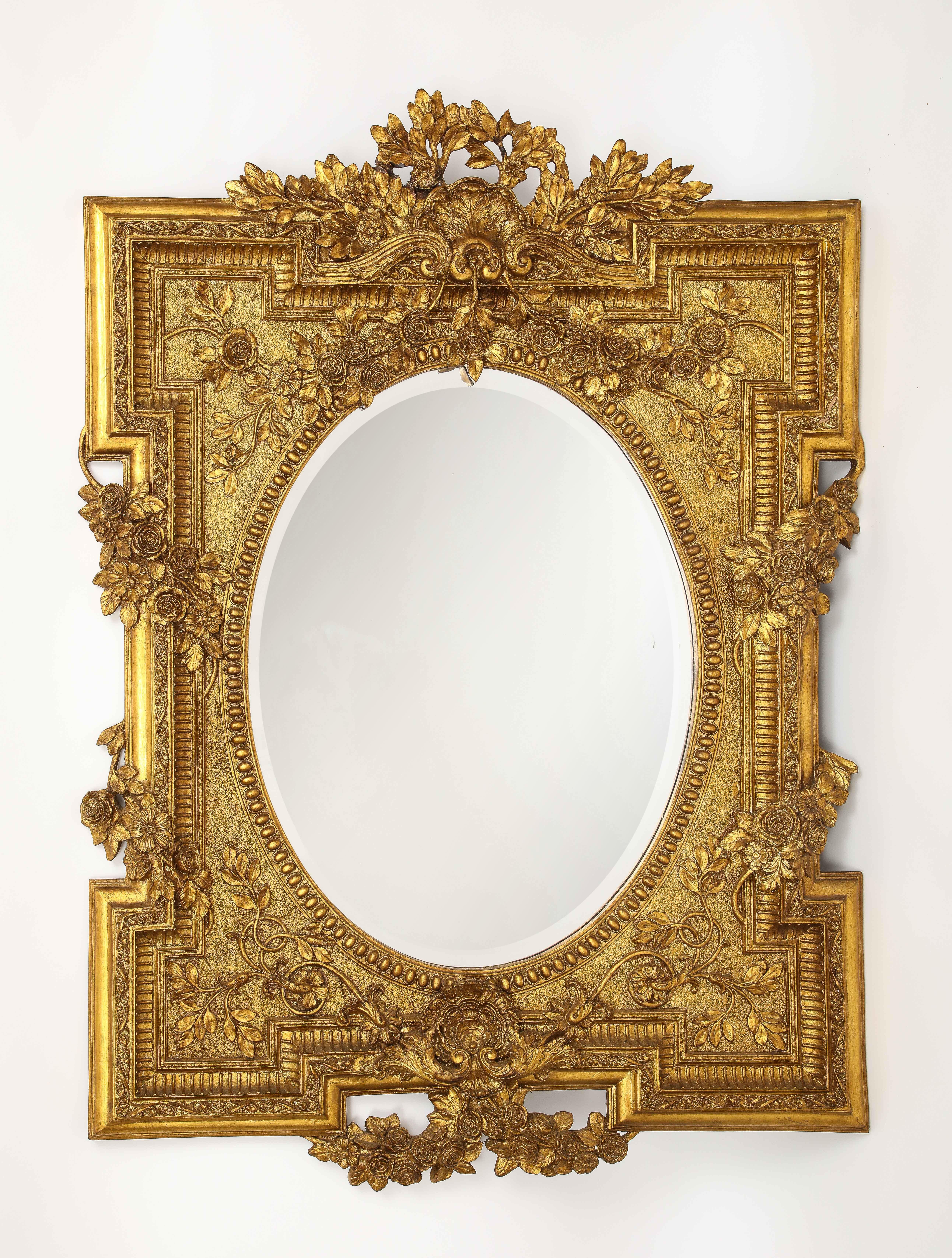 Merveilleux miroir biseauté en bois doré de style Louis XVI des années 1950, sculpté à la main avec des motifs de vignes florales. Le cadre en bois doré est magnifiquement sculpté à la main et magnifiquement doré à l'or 24K. La qualité et la