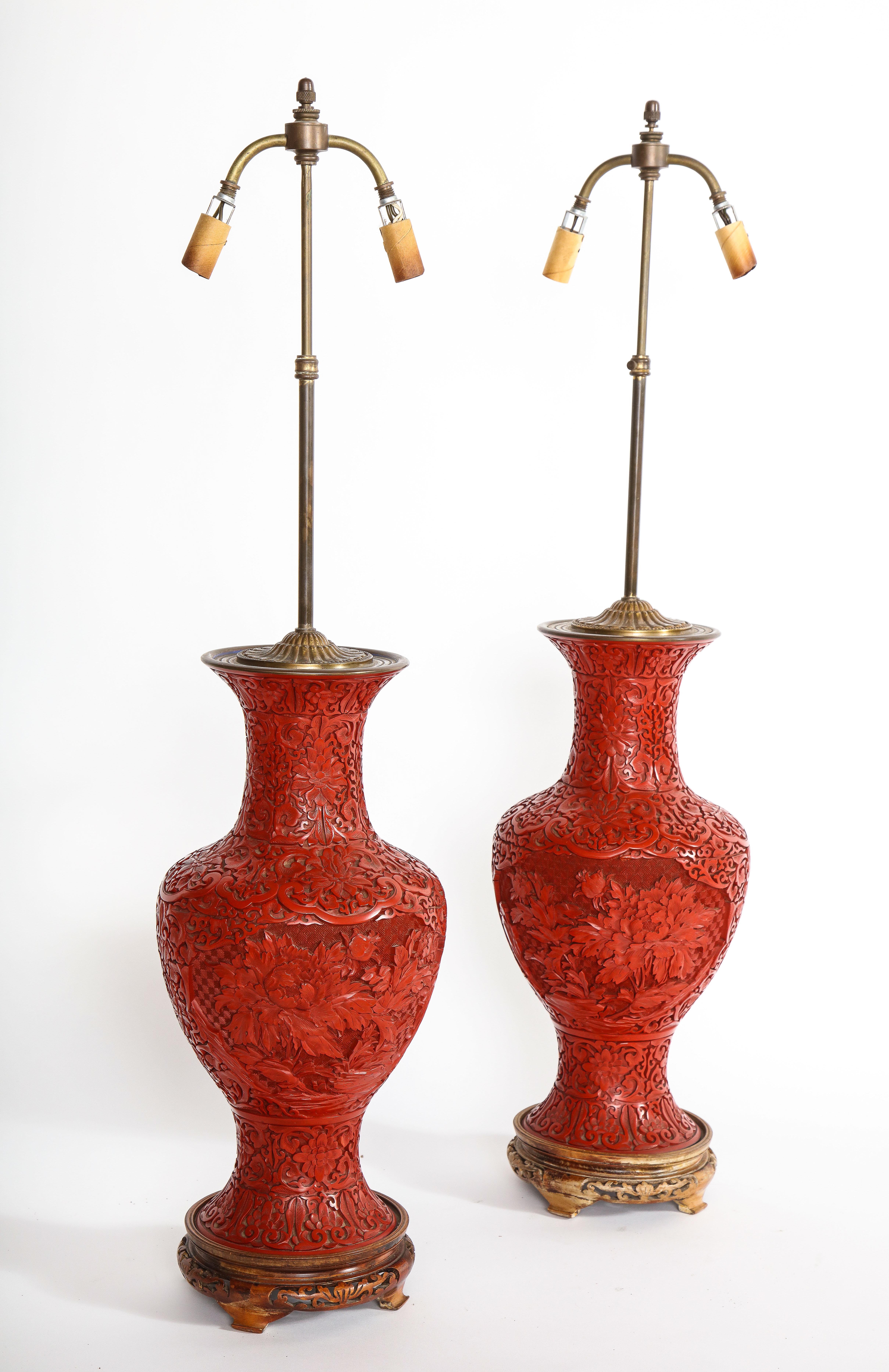 A marvelous pair of hand carved antique Chinese cinnabar vases mounted as lamps. The body, neck and bottom of the vases are densely carved with various floral sprays including peony, chrysanthemum and camellia. The entirety of each vase is
