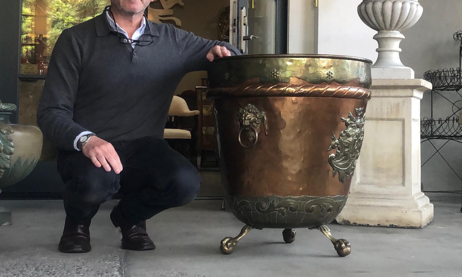 This large tapering vessel with applied armorial crests to front and back all flanked by bold lion ring handles; raised on 3 claw-and-ball feet.