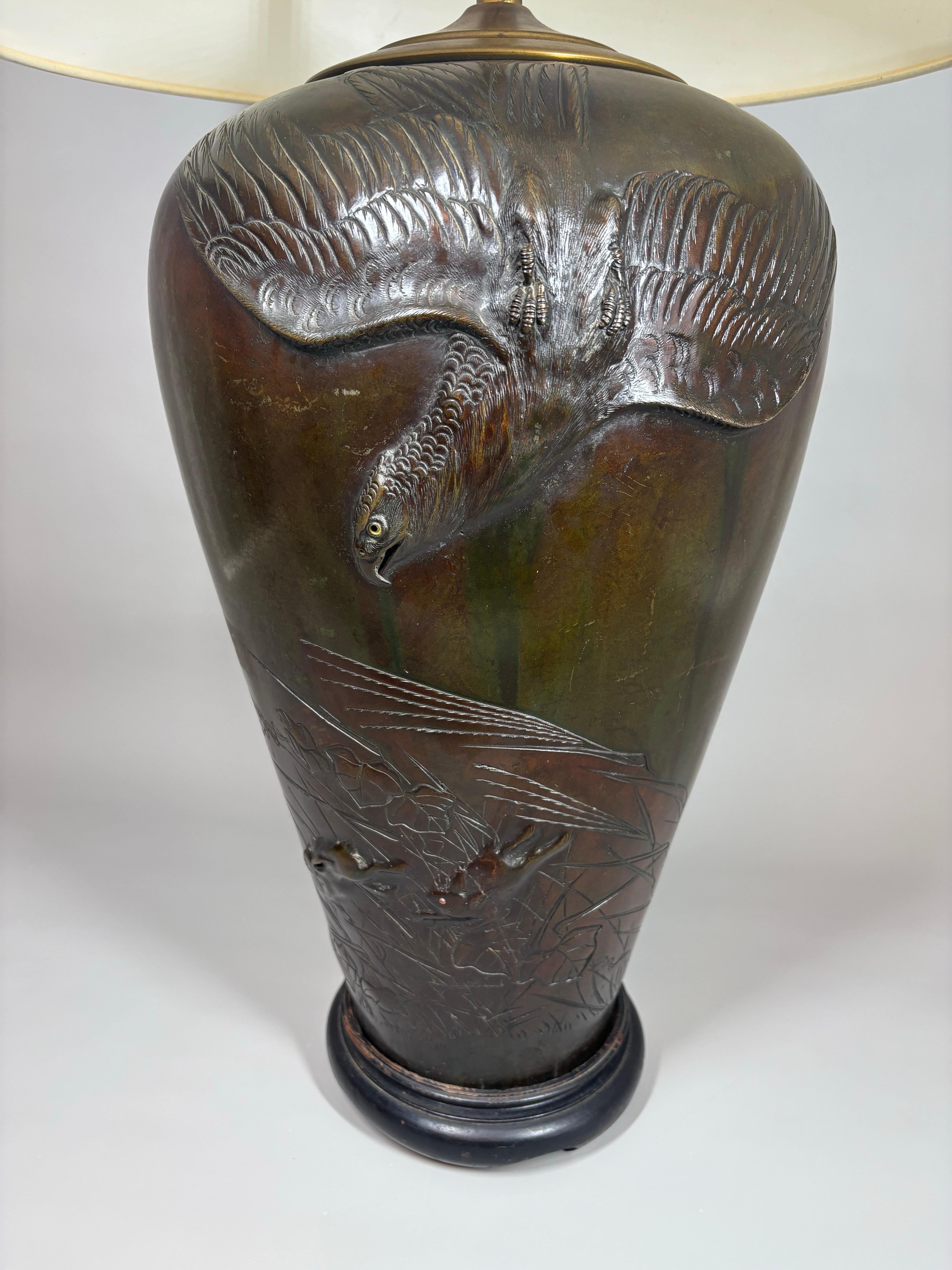 
Grand vase japonais en bronze finement moulé de la fin du XIXe siècle, datant de l'ère Meiji (1868-1912), transformé par la suite en lampe.
Le vase présente une scène dramatique en bas-relief d'un oiseau de proie planant au-dessus de deux petits