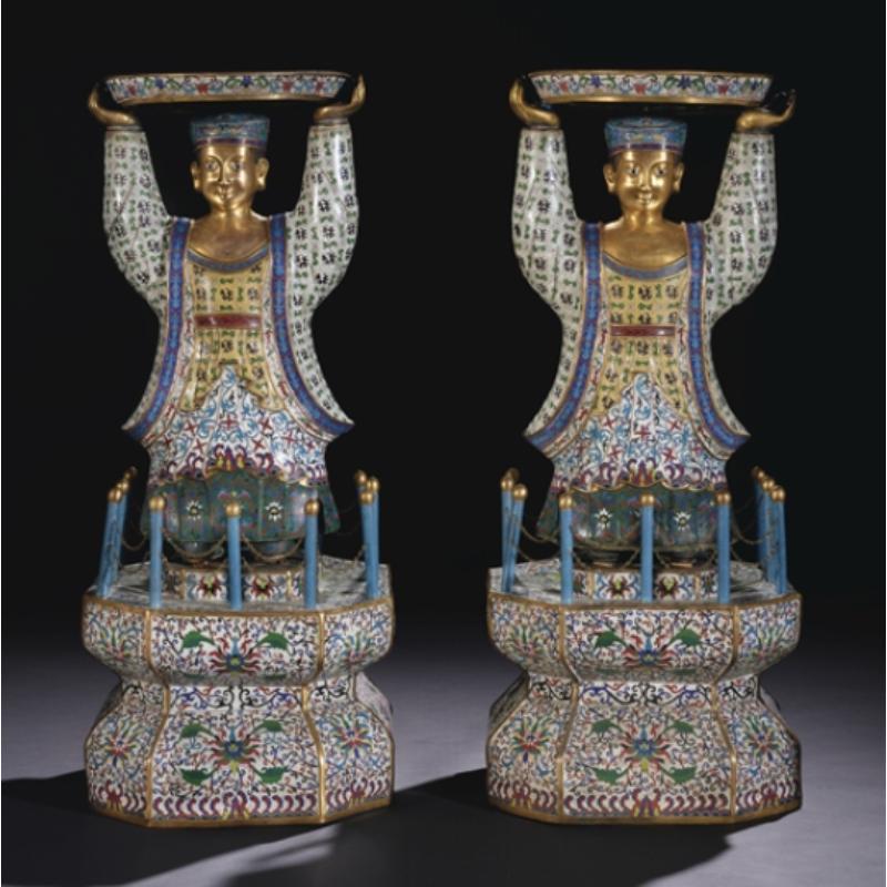 A rare and massive pair of Chinese cloisonne enamel figures of attendants, Qing Dynasty.

Each standing figure similarly depicted with hands raised overhead supporting a large circular tray, all raised on a tall octagonal waisted stand inserted