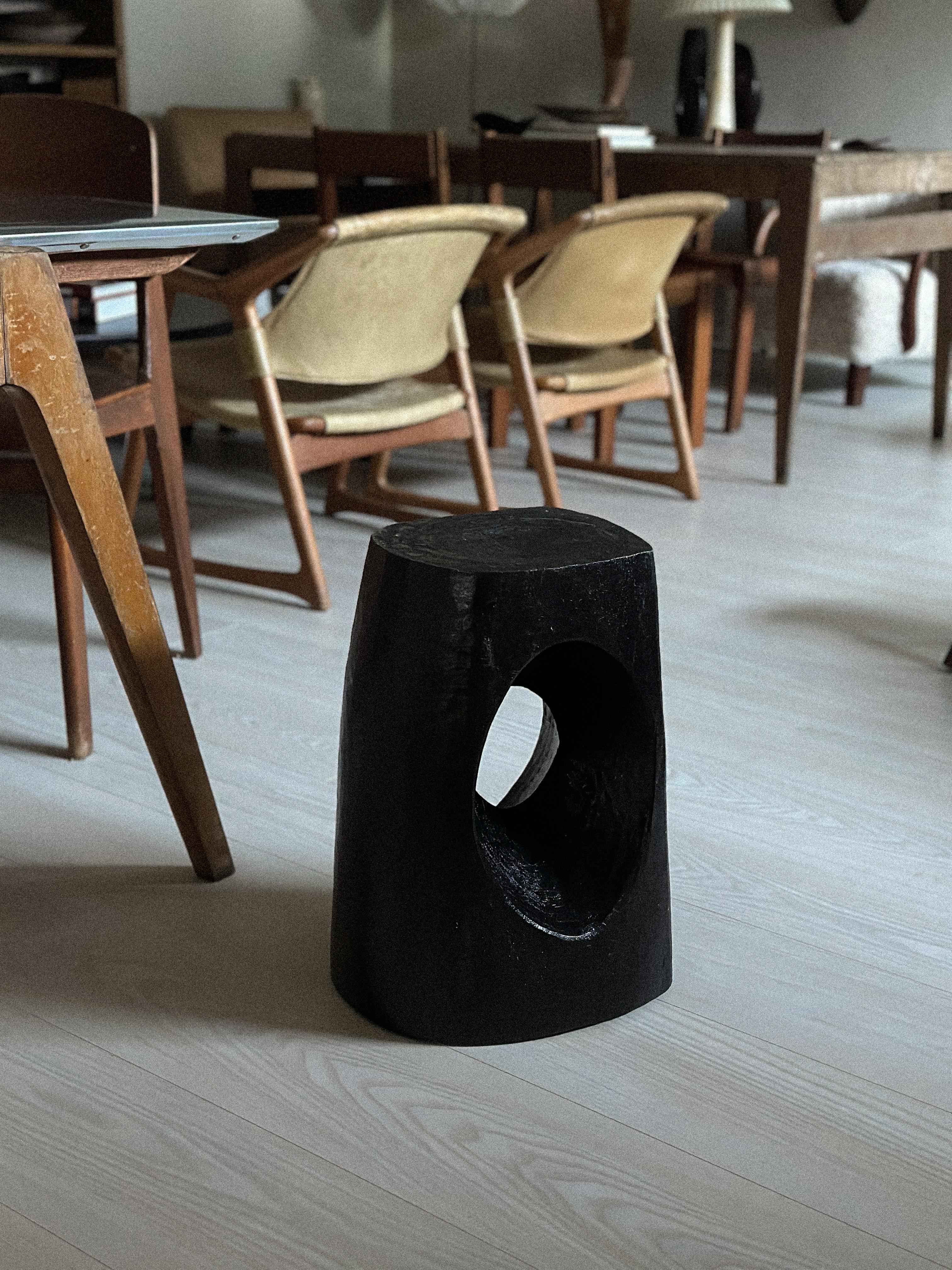 This mid-century stool is a true work of art, featuring a unique Wabi Sabi style that showcases the beauty of natural imperfections. Handcrafted with massive oak wood, this piece is ebonized to enhance its natural grain, resulting in a stunning