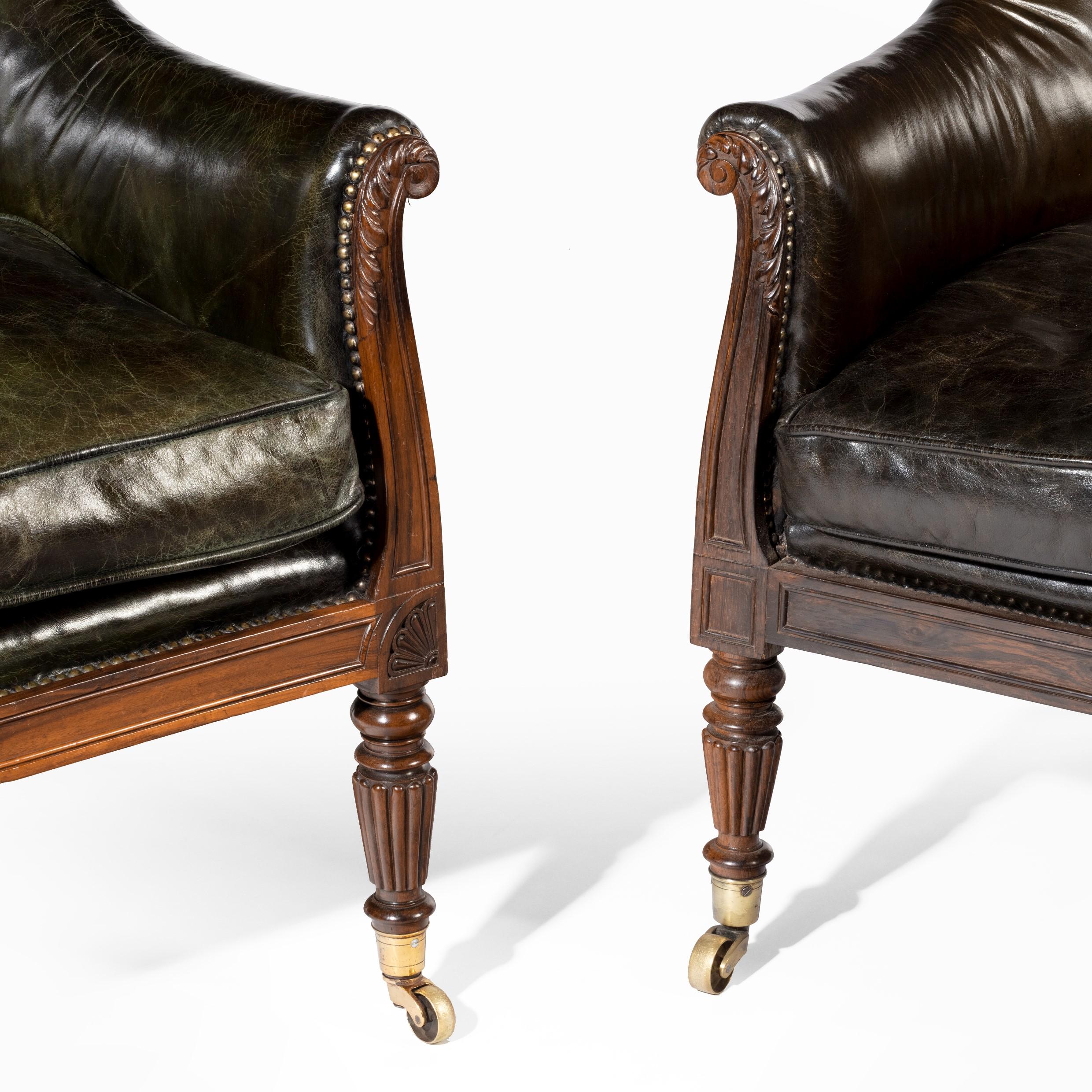 A matched pair of Gillows mahogany library chairs, each with an arched back wrapping round to scroll arms, above a buttoned loose cushion and paneled seat rail, on turned and reeded front legs and outswept back legs, all with brass caps and castors,