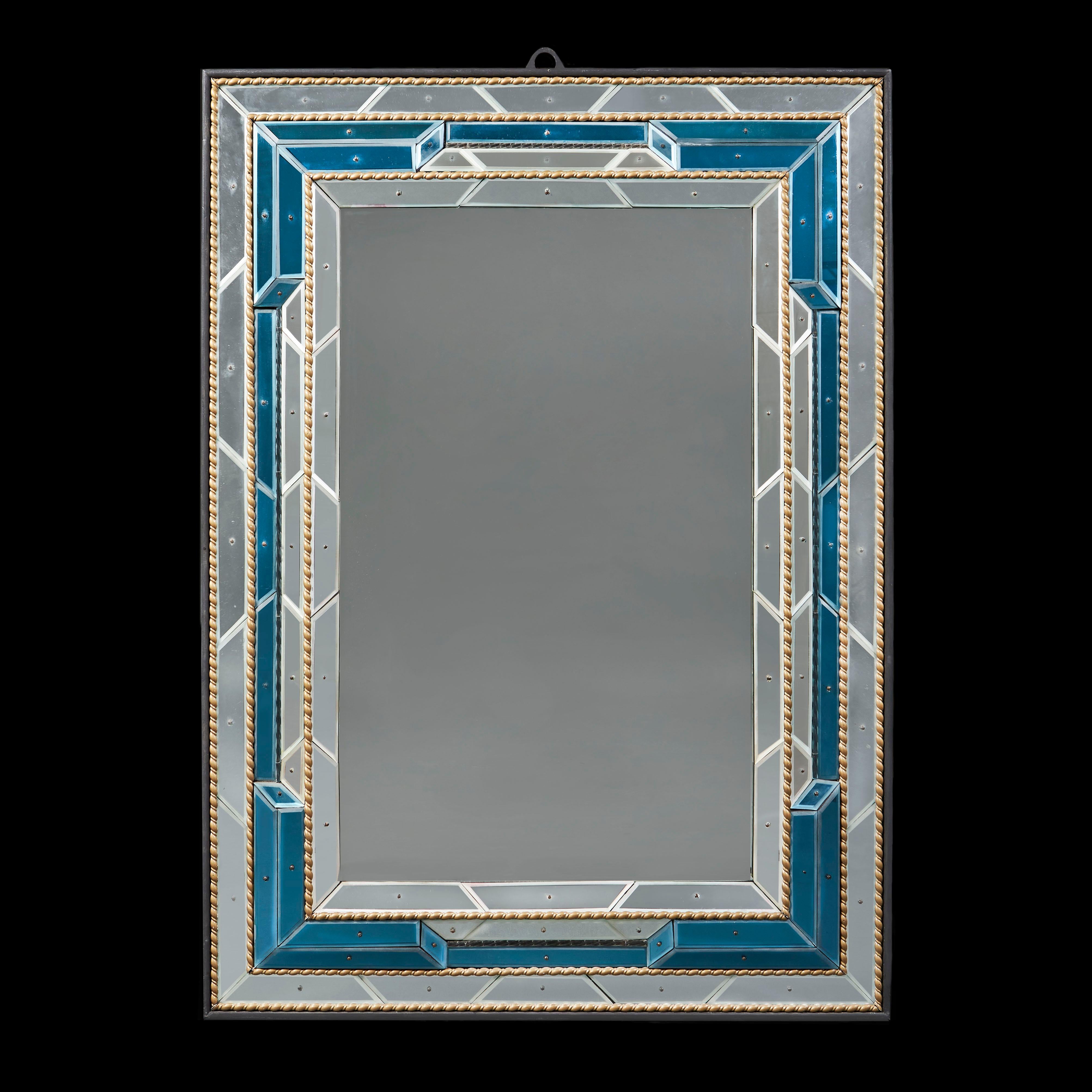 A fine matched pair of overscale mid-century Venetian mirrors with blue glass borders and segmented border frames, some variation in colour within the blue coloured glass panels, with ebonised frames and gilded beading, with aged mercury glass