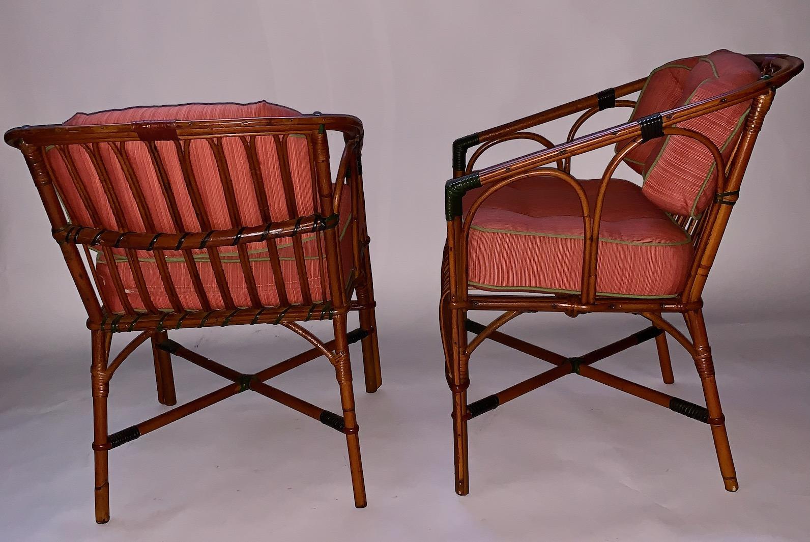 A very comfortable pair of rattan arm / dining chairs, American, C. 1 930s with newly upholstered back and seat cushions upholstered in Sunbrella outdoor fabrics in Papaya with Cilantro fabric welting, both the back and bottom cushions are attached