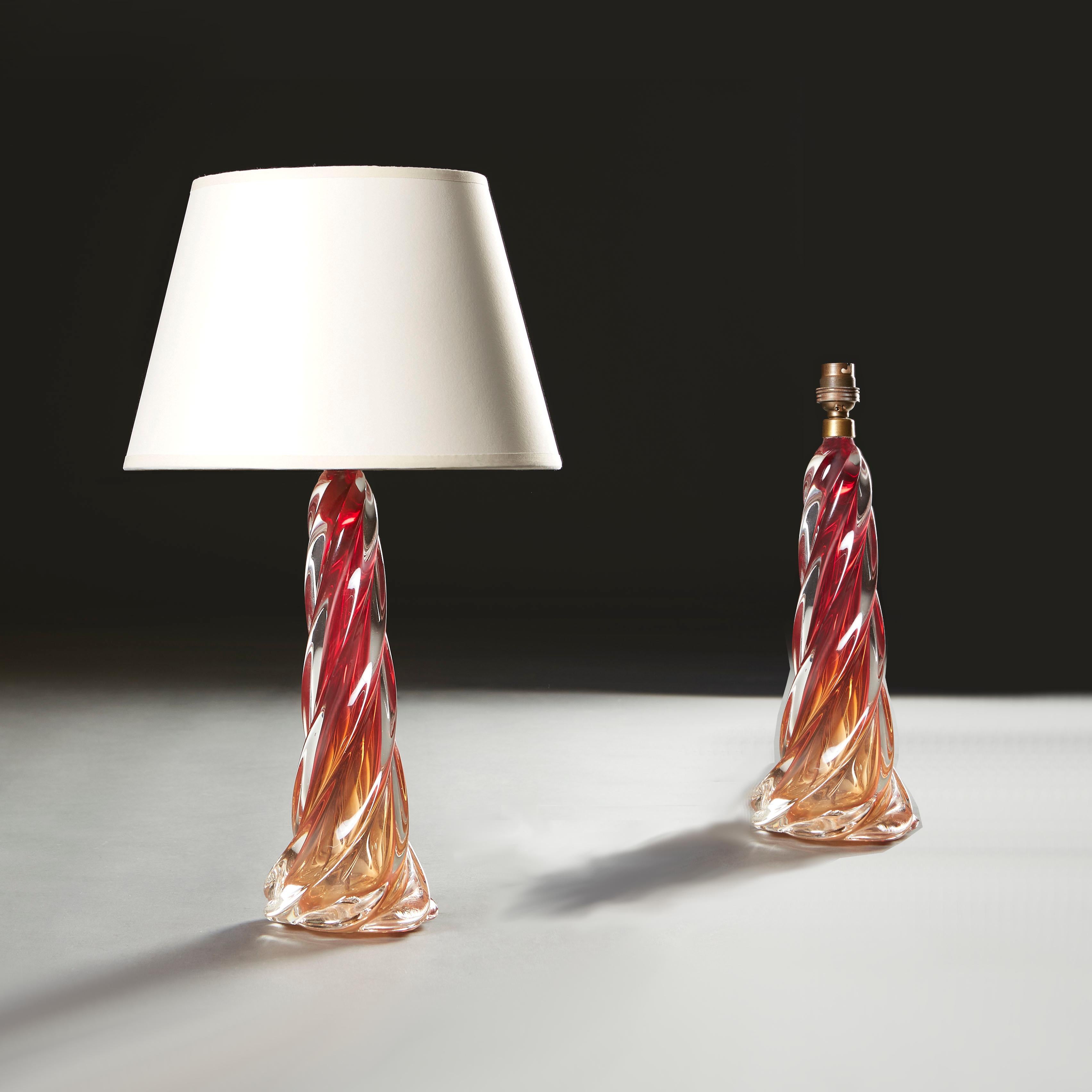 A matched pair of mid-twentieth century Murano glass lamps, the red and amber glass stem of spiral form, with circular base.

Currently wired for the UK, with twisted silk flex and torpedo switch, with brass bayonet cap bulb fitting. Please enquire
