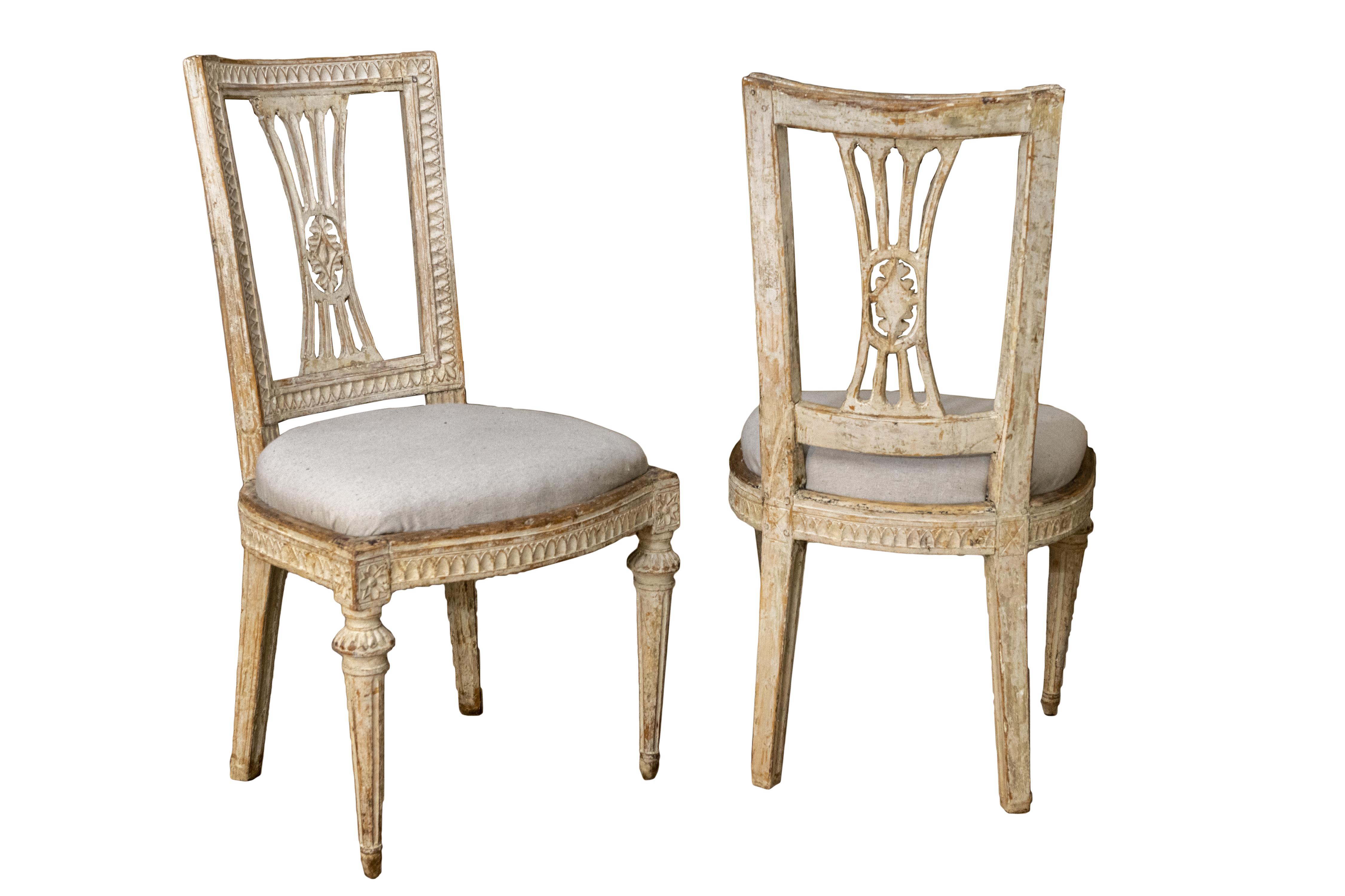 A matched set of early 19th century painted and hand carved Gustavian dining chairs.
Two arm chairs and four chairs. The four chairs have drop in upholstered seats.
The chairs are hand carved all around the back and seats and arms. The four arms