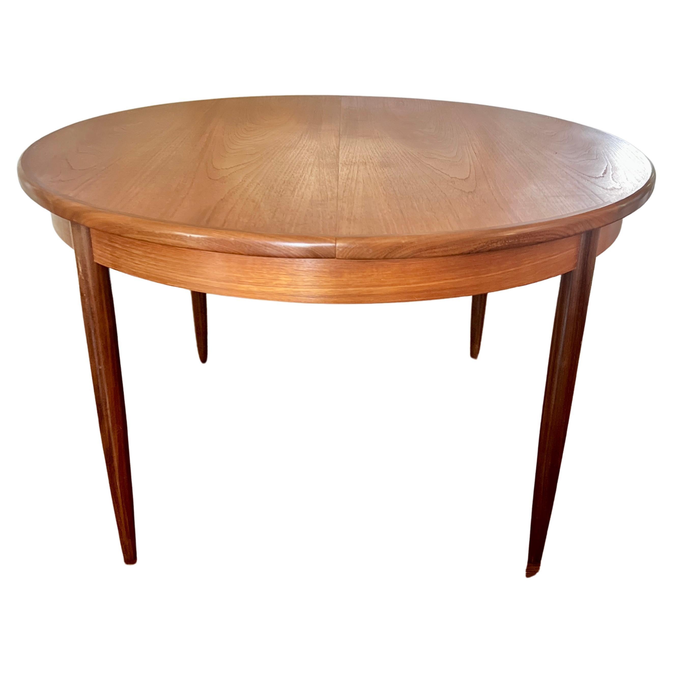 A MCM round teak dining table by G plan, with one 18" pop up leaf 