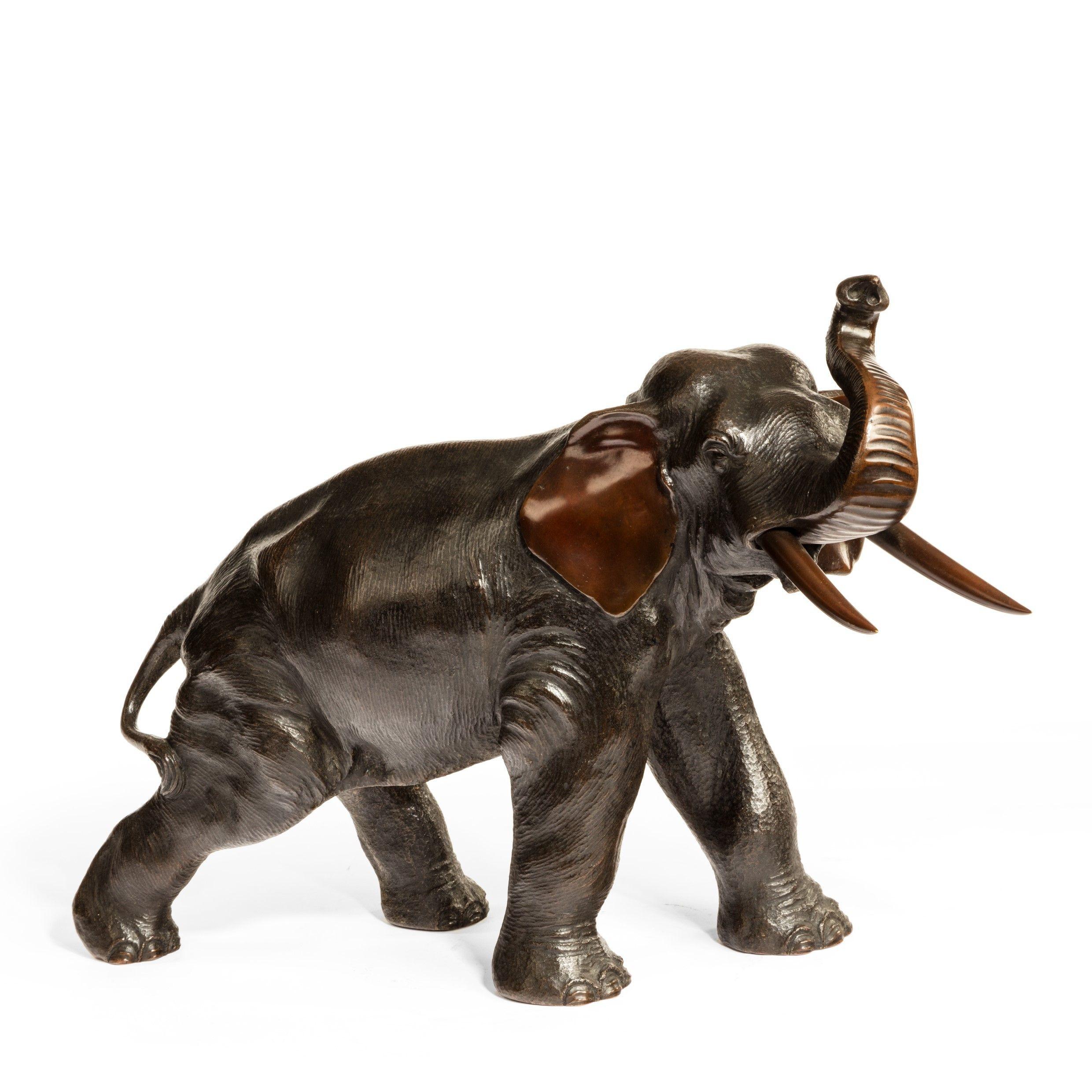 A Meiji period bronze elephant by Genryusai Seiya, the powerful animal striding forward with trunk raised, the insides of the ears, trunk and tusks patinated reddish brown, on a rootwood base, signed in a seal ?????? Genryusai Seiya zo [Made by