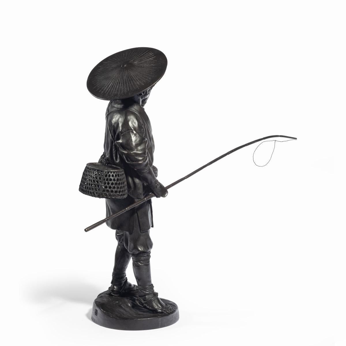 A Meiji period bronze of a cricket catcher, shown holding a whistle to his mouth with his left hand and a long rod in his right hand, wearing traditional clothing with a wide-brimmed hat and a creel slung across his back, signed in a seal. Japanese,