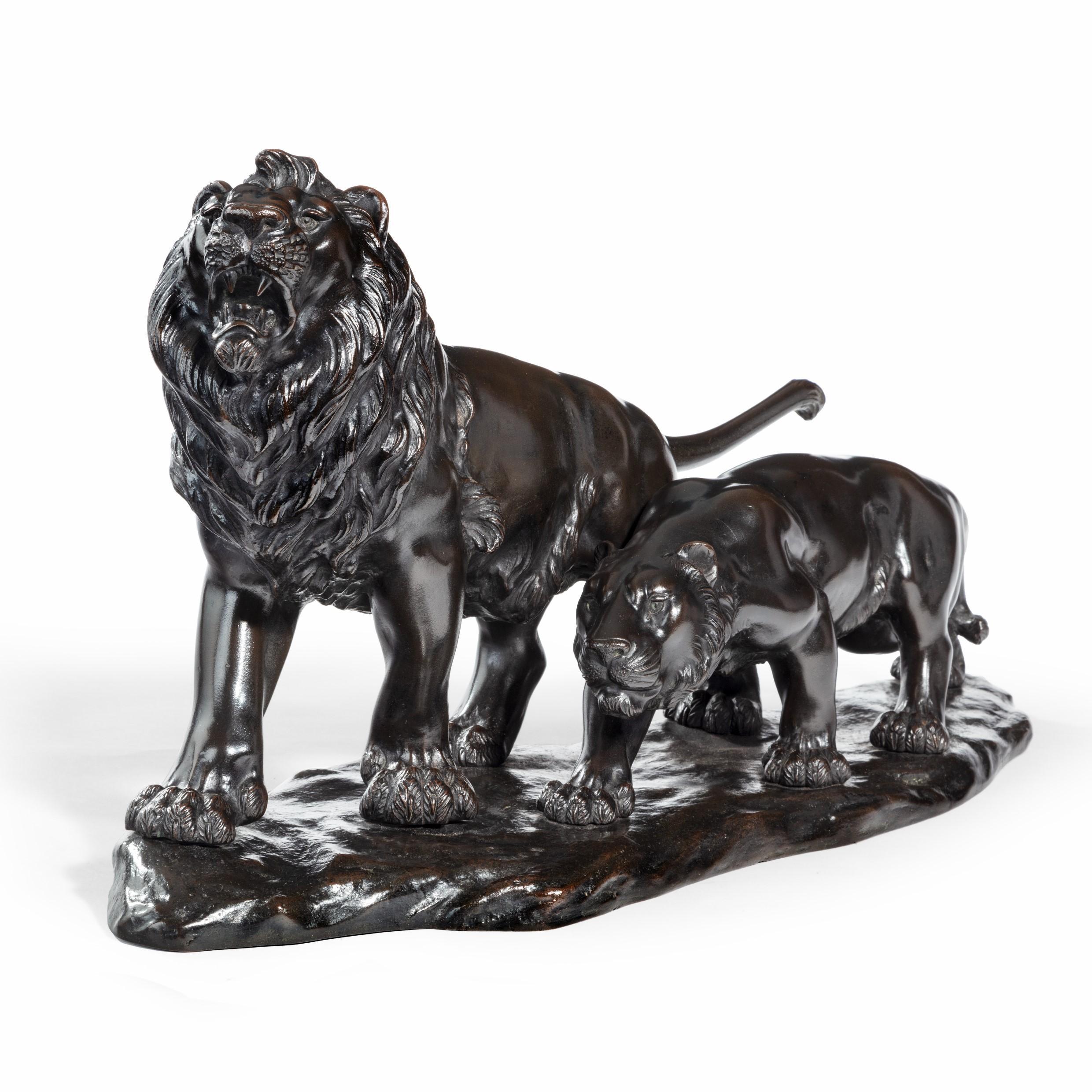 A Meiji period bronze study of a lion and lioness, the lion striding forward and snarling with the lioness slinking by his side, on a root-wood base. Signed in a seal, ‘Genryusai Seiya’. Japanese, circa 1890. Footnote: Genryusai Seiya was the master