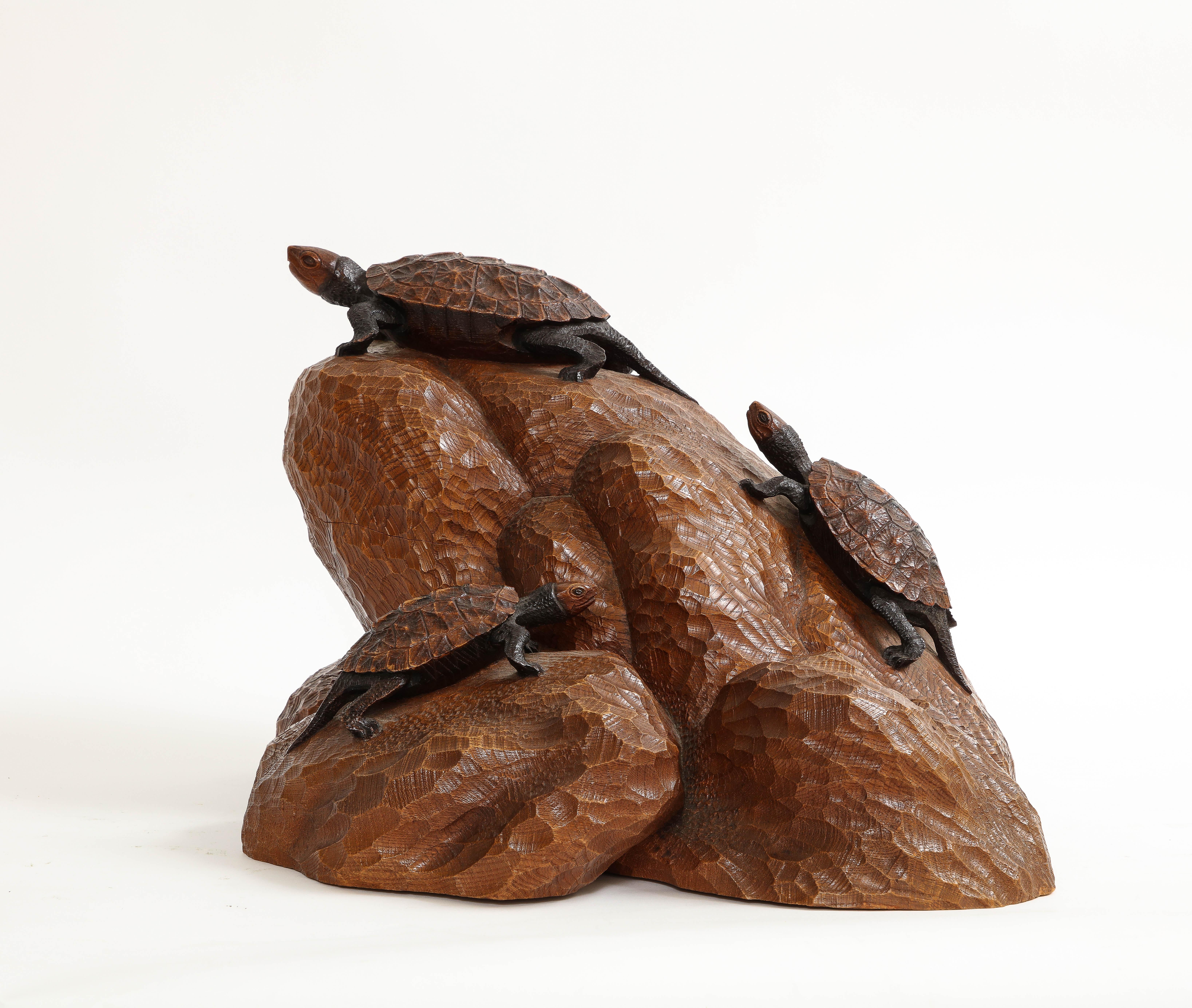 Escultura japonesa de tortuga tallada a mano del periodo Meiji. Todo el objeto está tallado en una gran pieza maciza de madera dura.  En la madera están talladas a mano tres tortugas.  La base de madera es emblemática de un gran peñasco.  Se ve a
